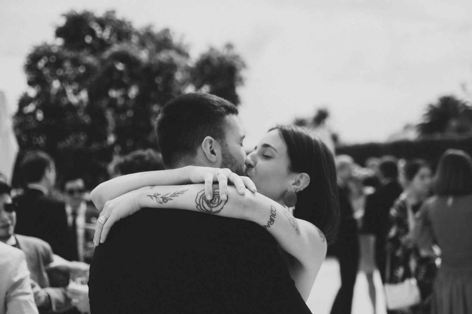 Black and white photograph of an intimate wedding celebration with dancing and embraces.