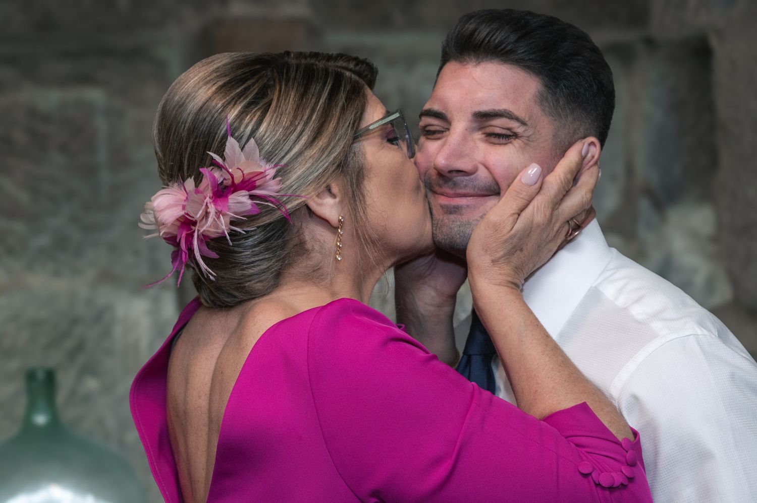 A couple shares an intimate moment against a stone wall background.