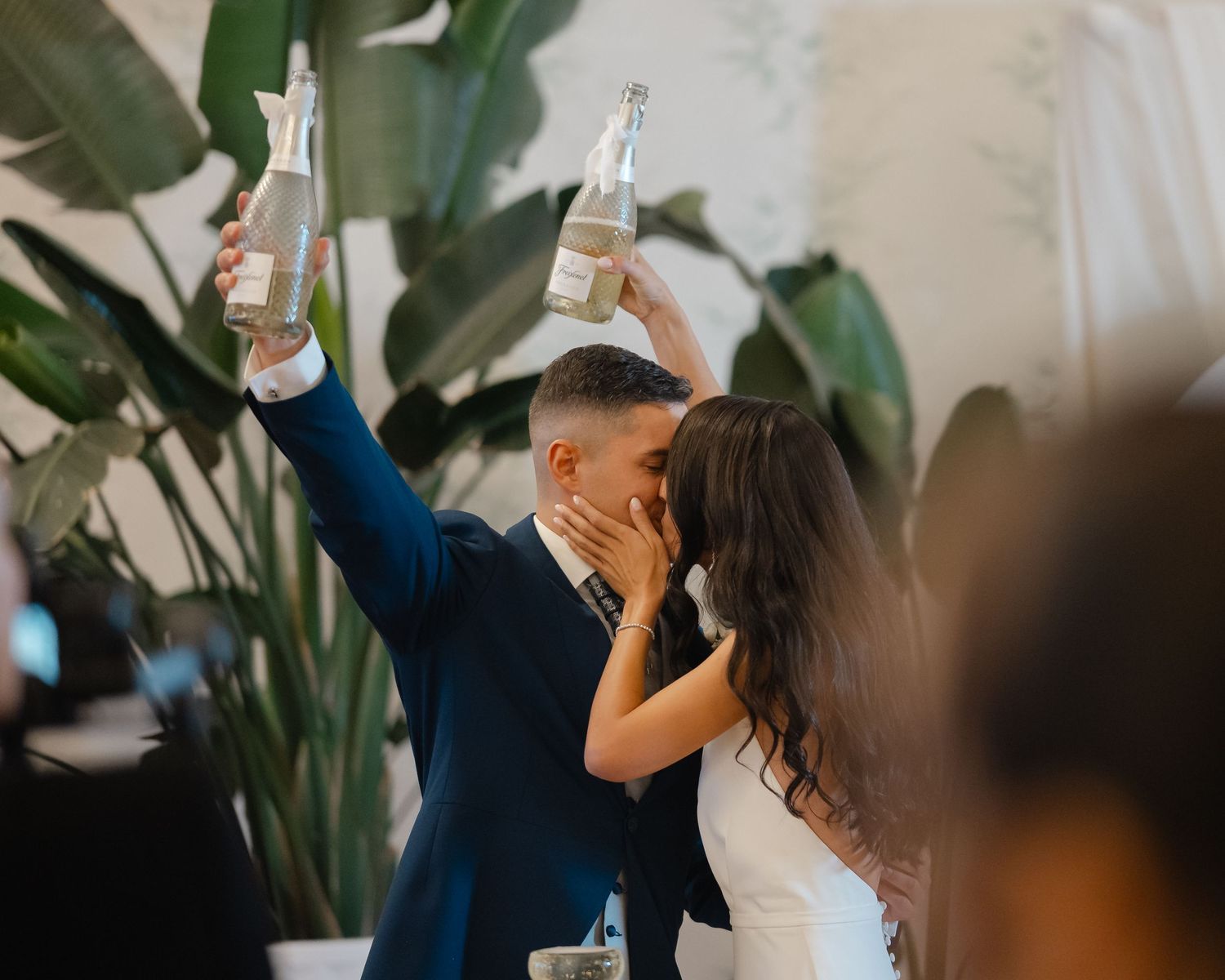 Wedding guests raise their glasses in celebration during a toast at an elegant indoor reception.