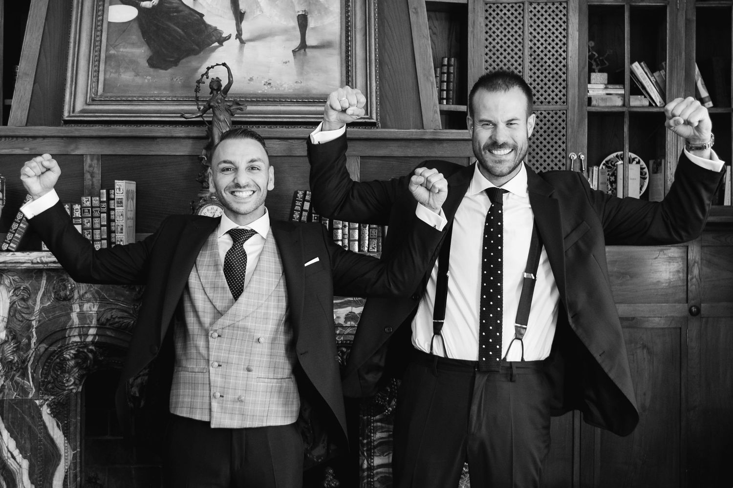 Two people in formal attire celebrating with raised arms in a black and white photograph.