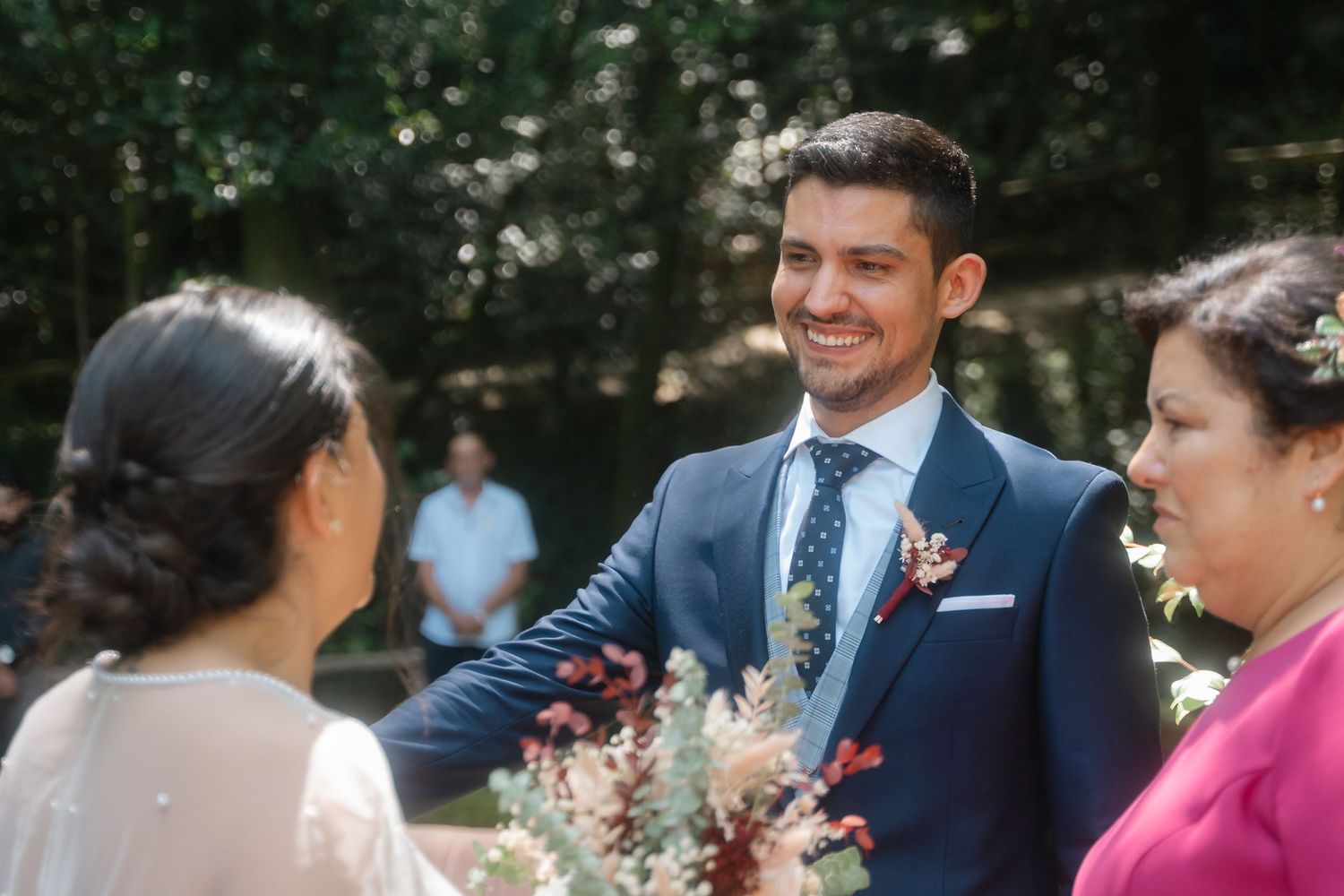 A joyful moment at an outdoor wedding ceremony with guests interacting and pink floral decorations.