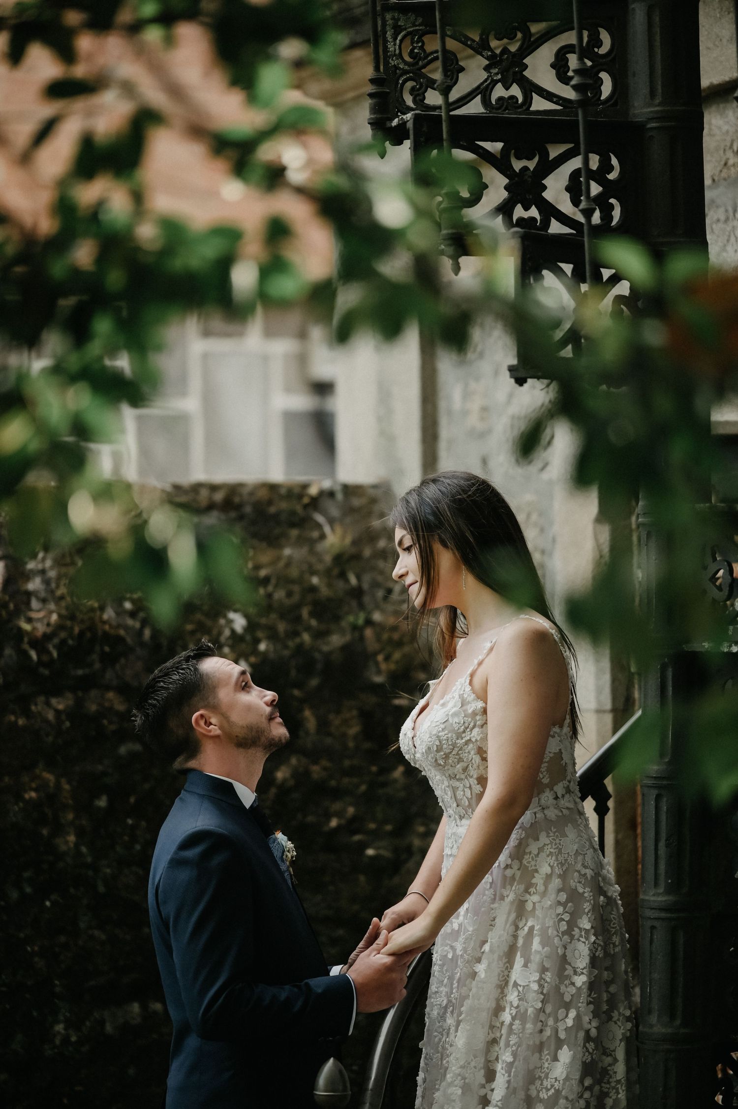 A romantic proposal moment captured in a garden setting with ornate architectural details and soft natural lighting.