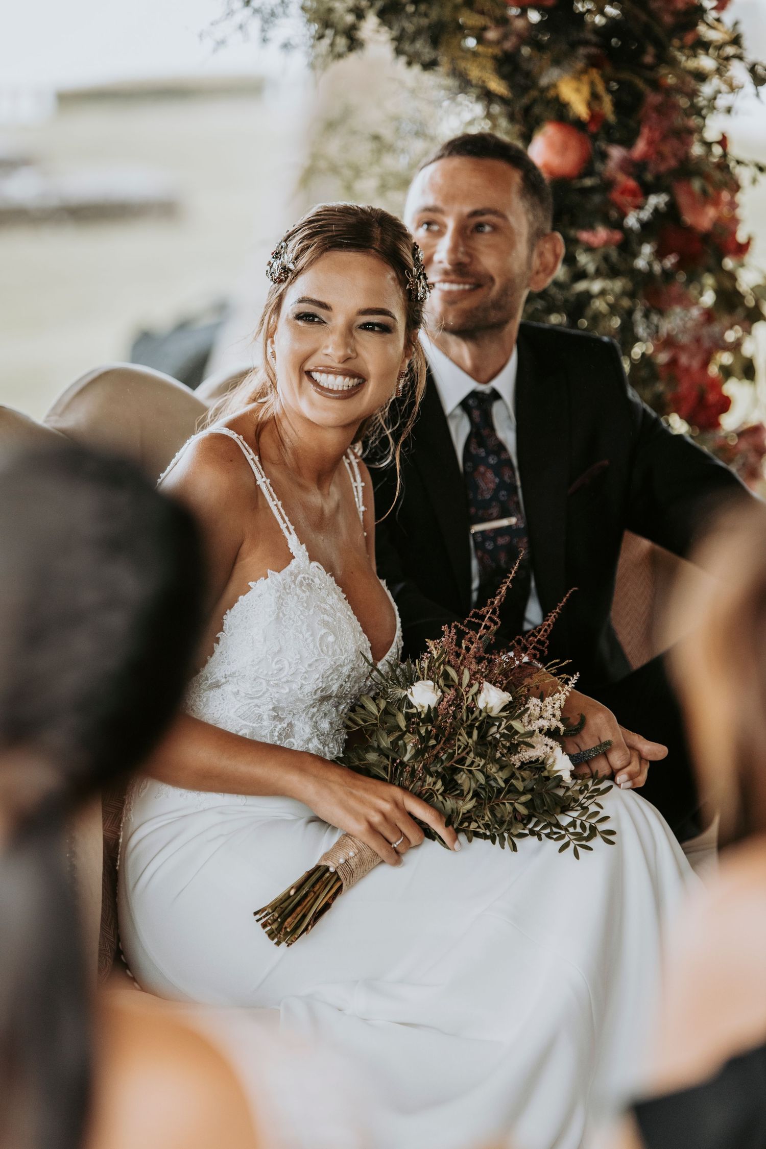 Candid wedding moment showing joyful laughter and emotion during outdoor ceremony with floral decorations.