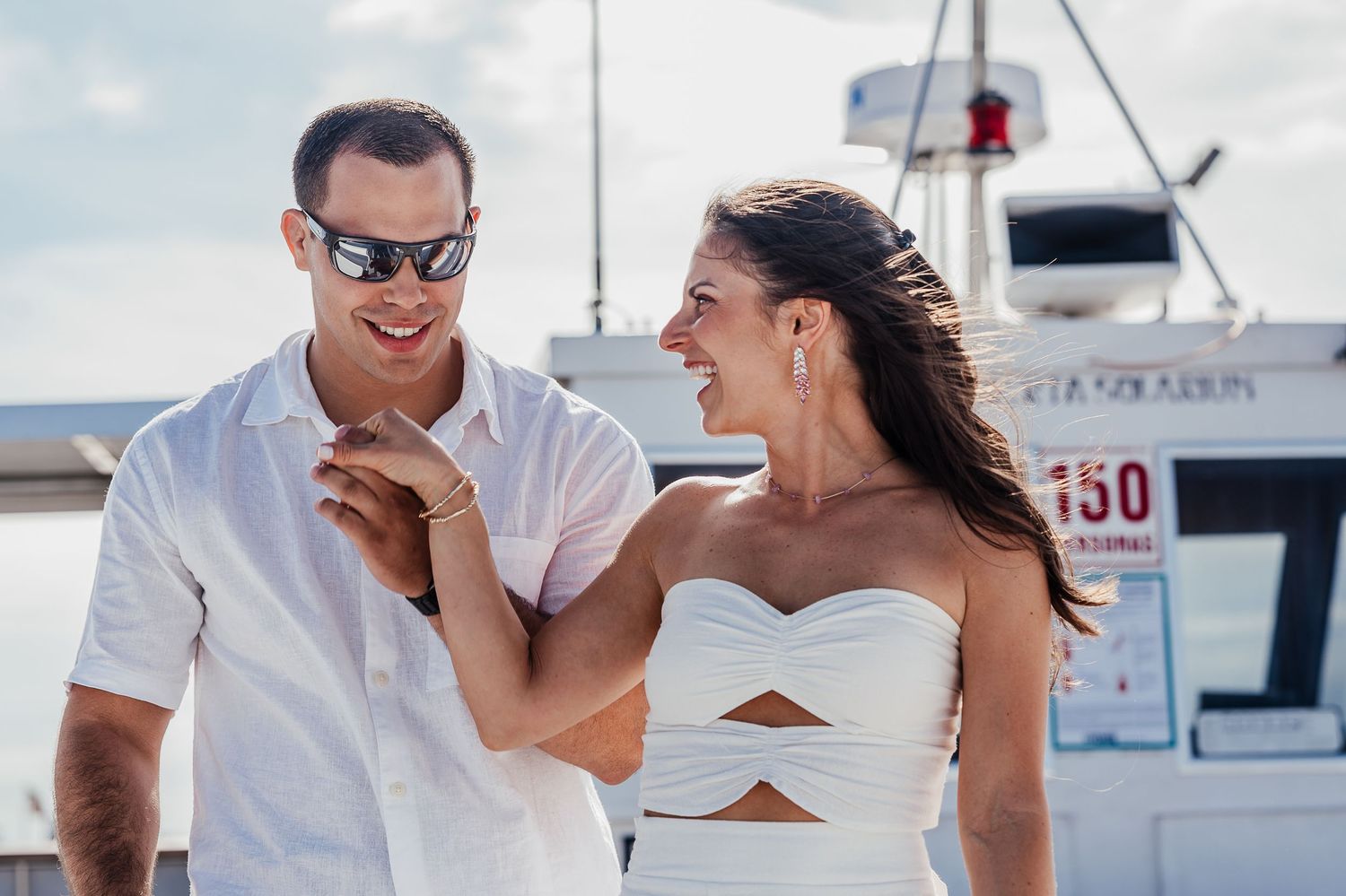 People enjoying a sunny day on a boat deck while sharing drinks and laughs together.