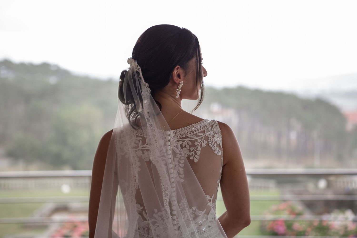 Back details of a lace wedding dress with buttons and sheer fabric.