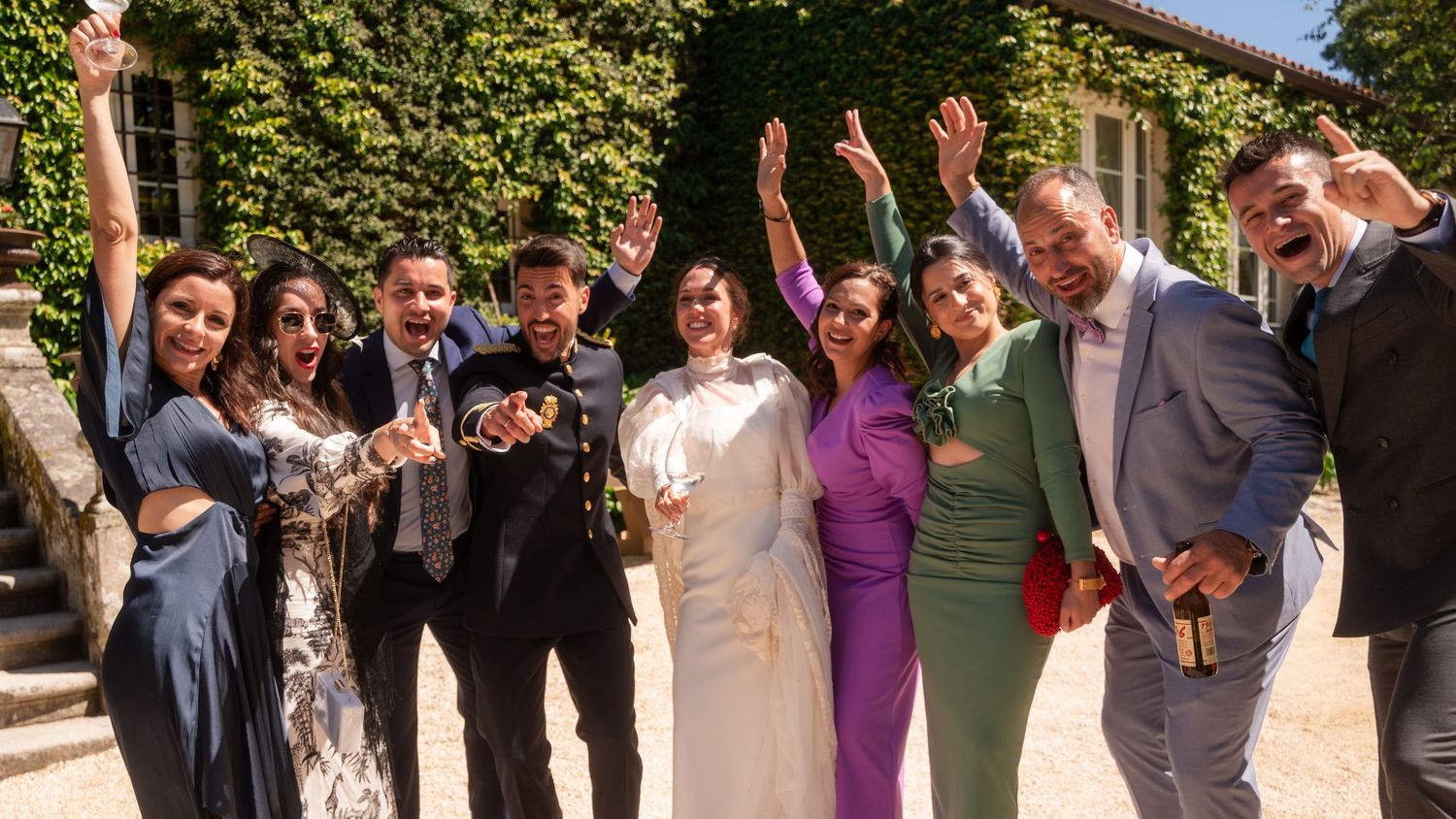 People celebrate joyfully outdoors in formal attire with energetic poses against a natural backdrop.