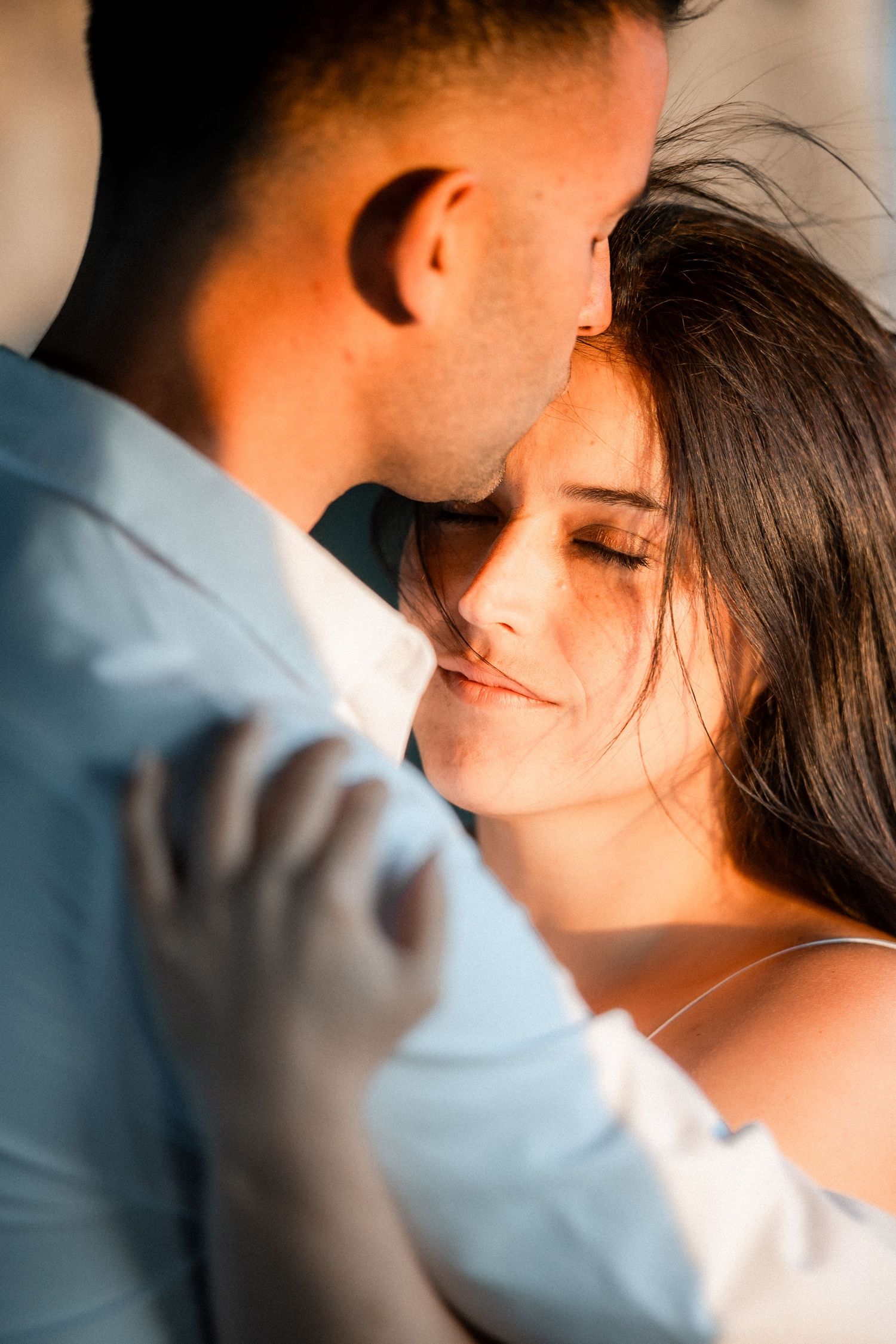 Close-up intimate portrait of a couple in soft lighting with dreamy bokeh effect.