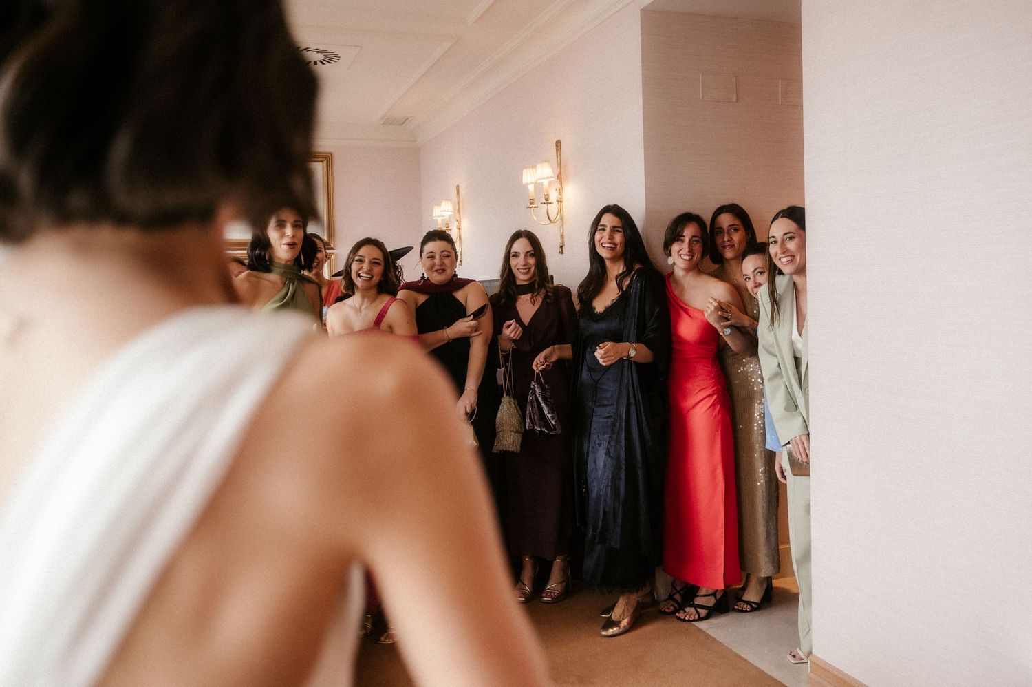 A wedding party gathers in a bright white room as they prepare for the ceremony and celebration.