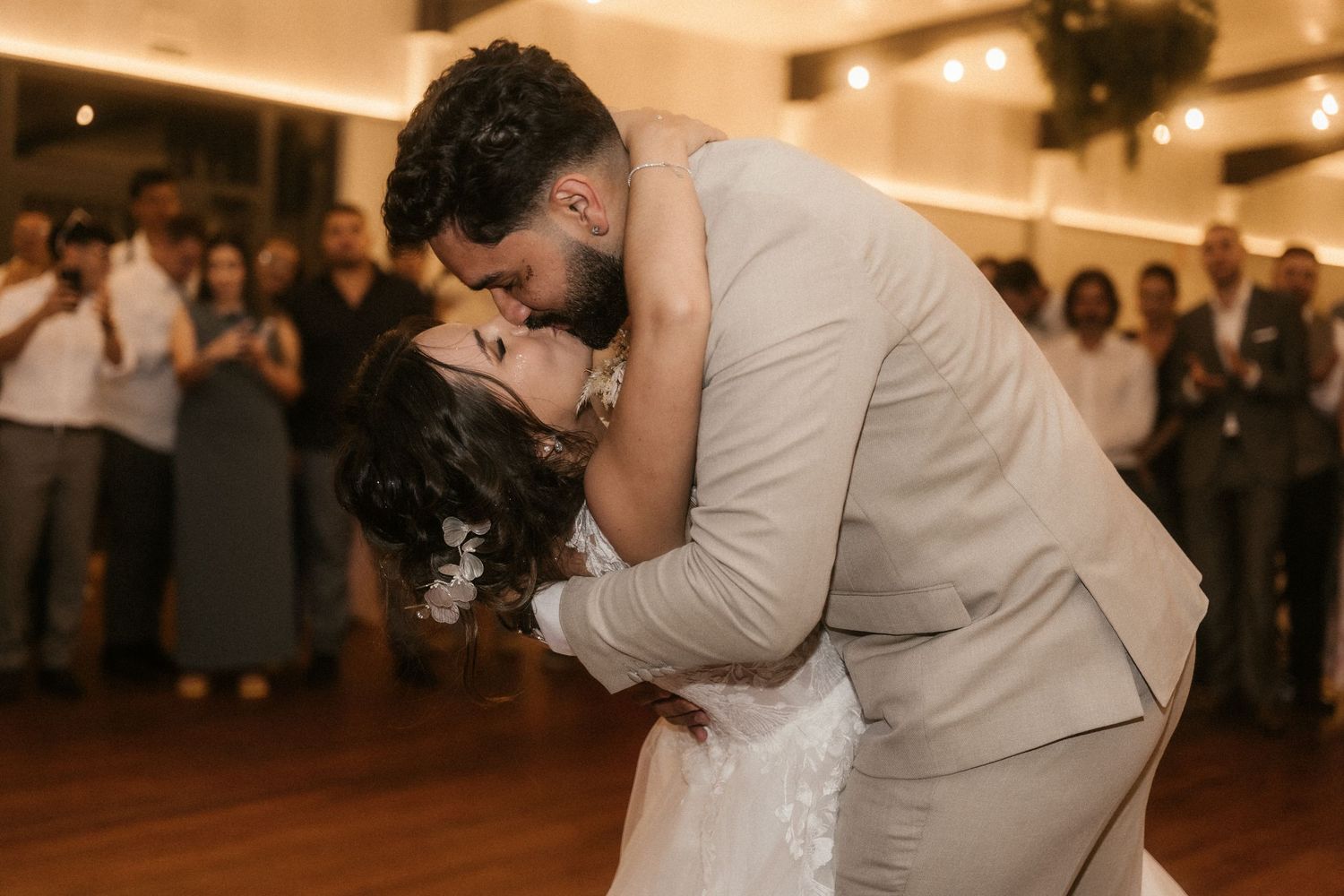 A couple shares an intimate dance moment at their wedding reception surrounded by guests.