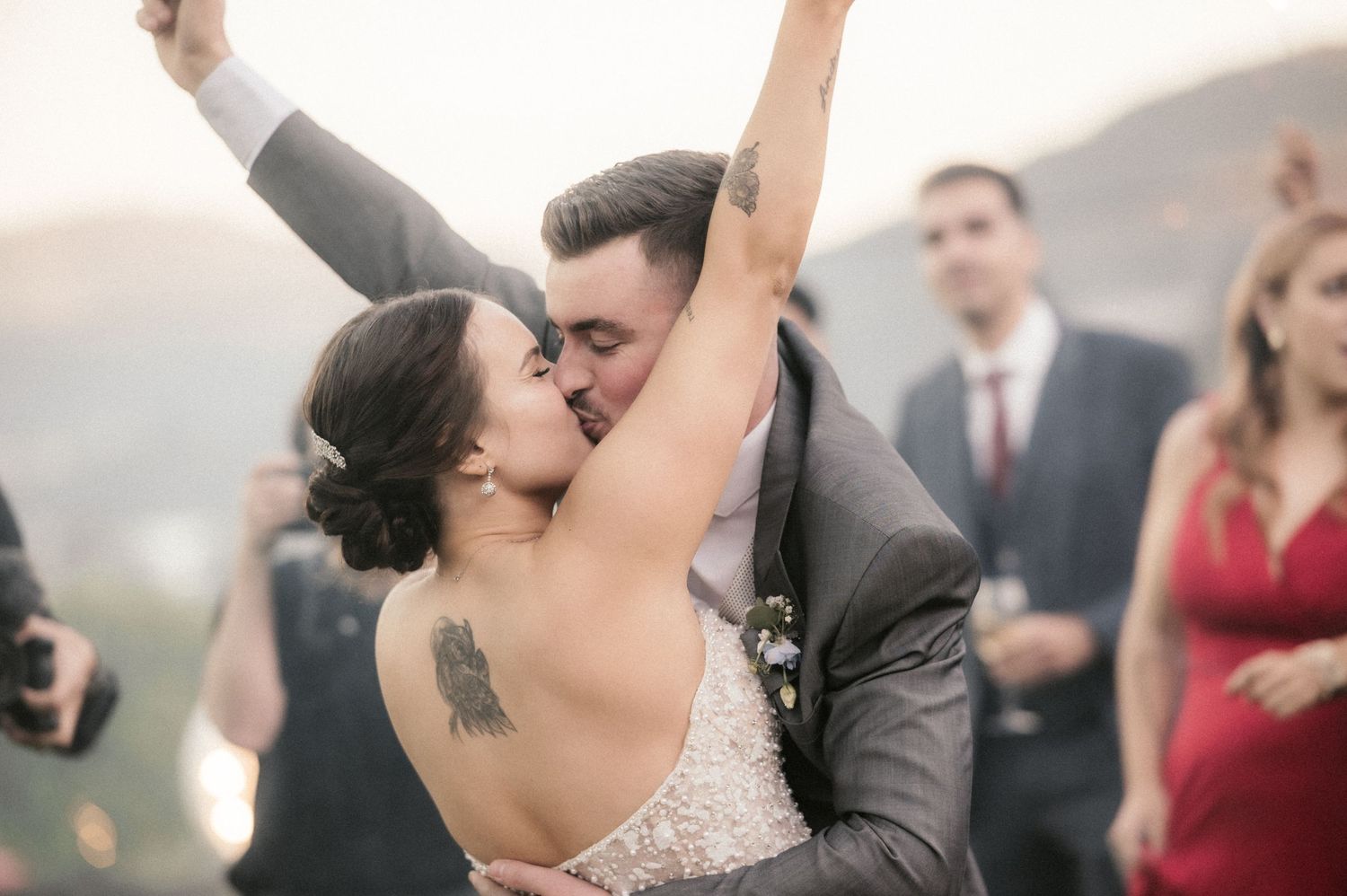 Bride and groom share romantic kisses in a series of candid wedding photos with guests in the background.