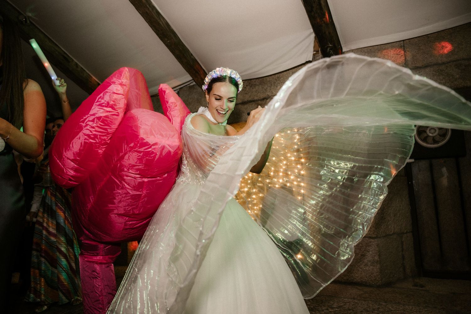 Wedding party dancing and celebrating in a festive indoor venue with pink decor accents.