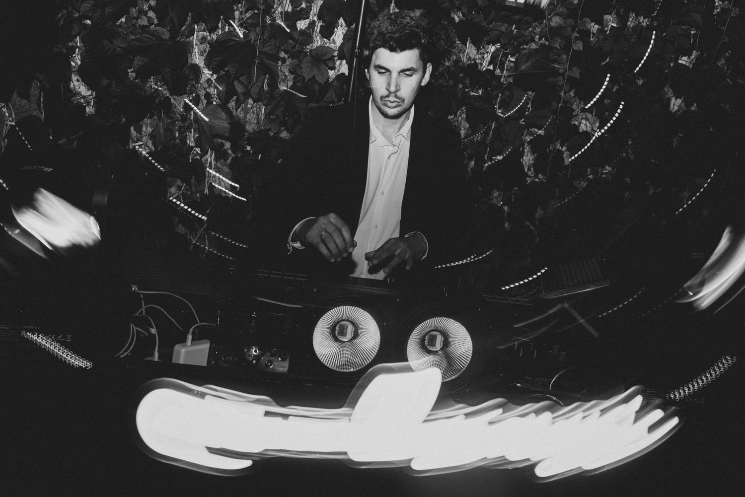 A black and white photograph shows a person performing on stage with dramatic lighting and a crowd in the background.