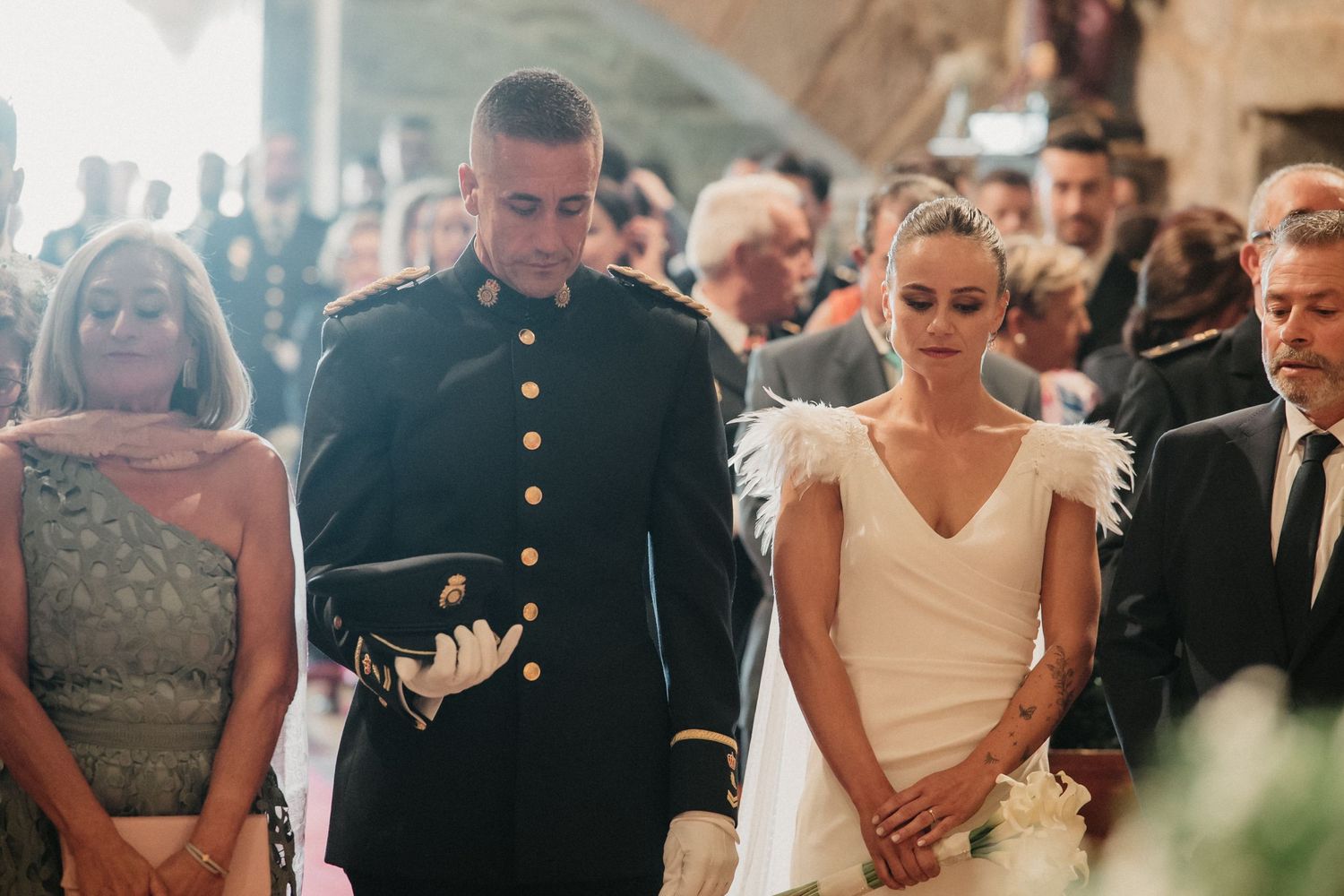 Elegant wedding ceremony with guests seated in rows as the couple exchanges vows in a bright indoor venue.