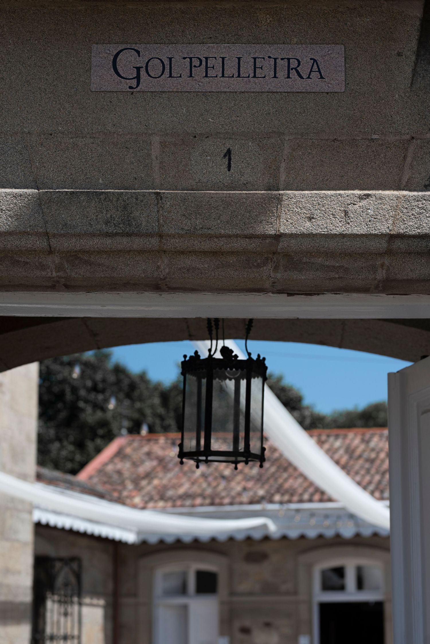 Architectural detail showing 'Golpelletra' text on a white Mediterranean-style building with terracotta roof tiles.