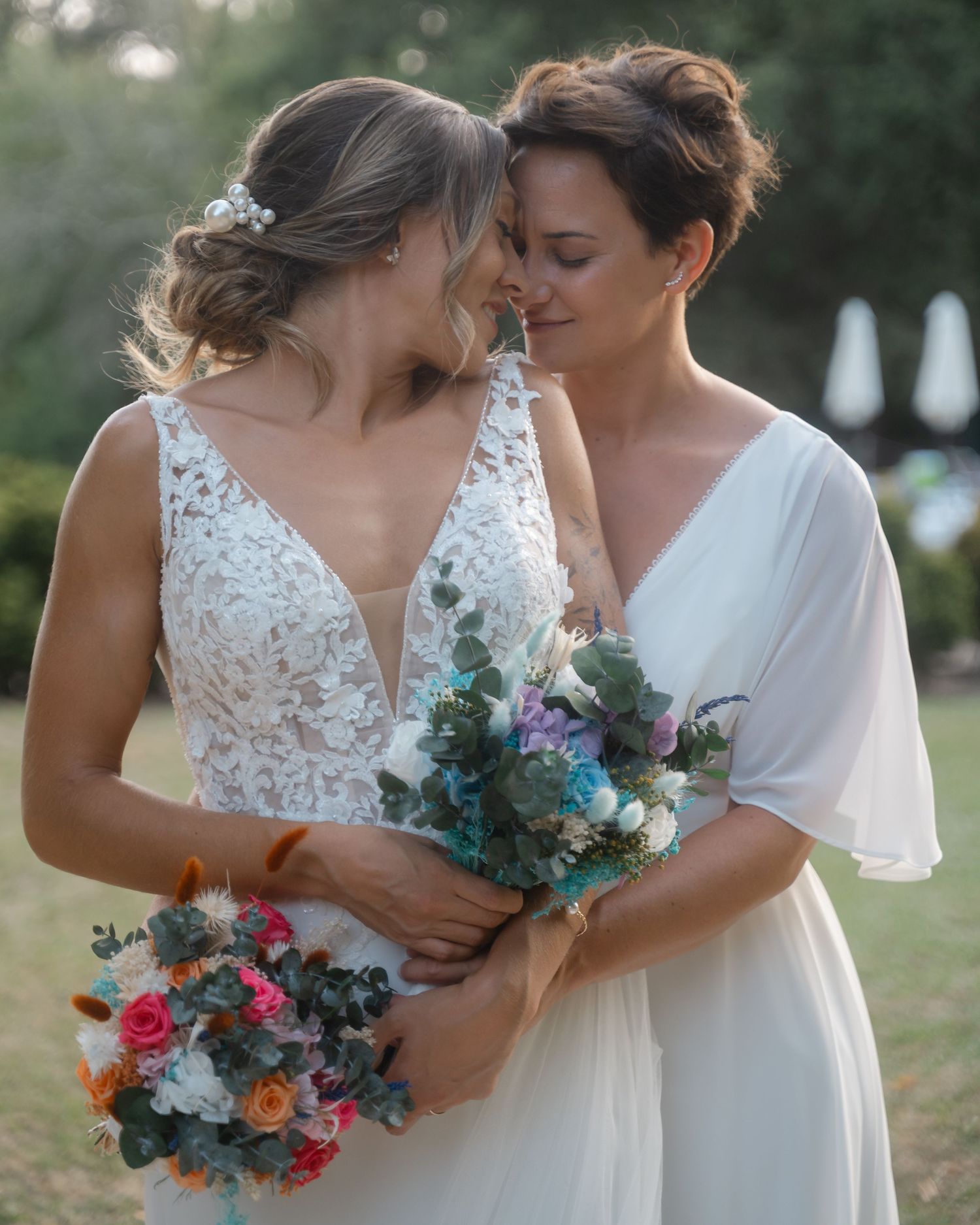 Two brides share an intimate moment while holding vibrant bouquets during their outdoor wedding.Wedding photographer Spain. Galicia.