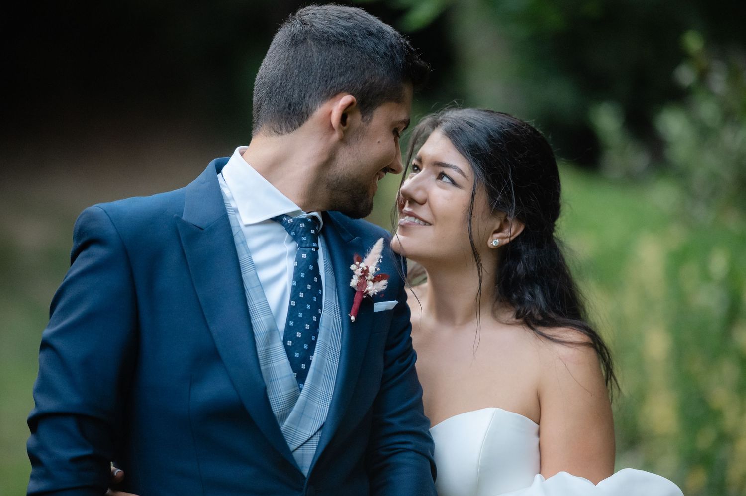 A romantic wedding portrait of a couple sharing an intimate moment outdoors.