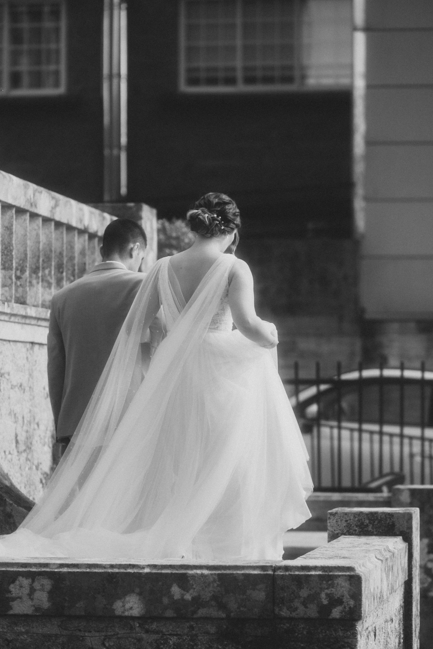 Black and white photo of wedding dresses sitting on a stone wall with flowing veils.