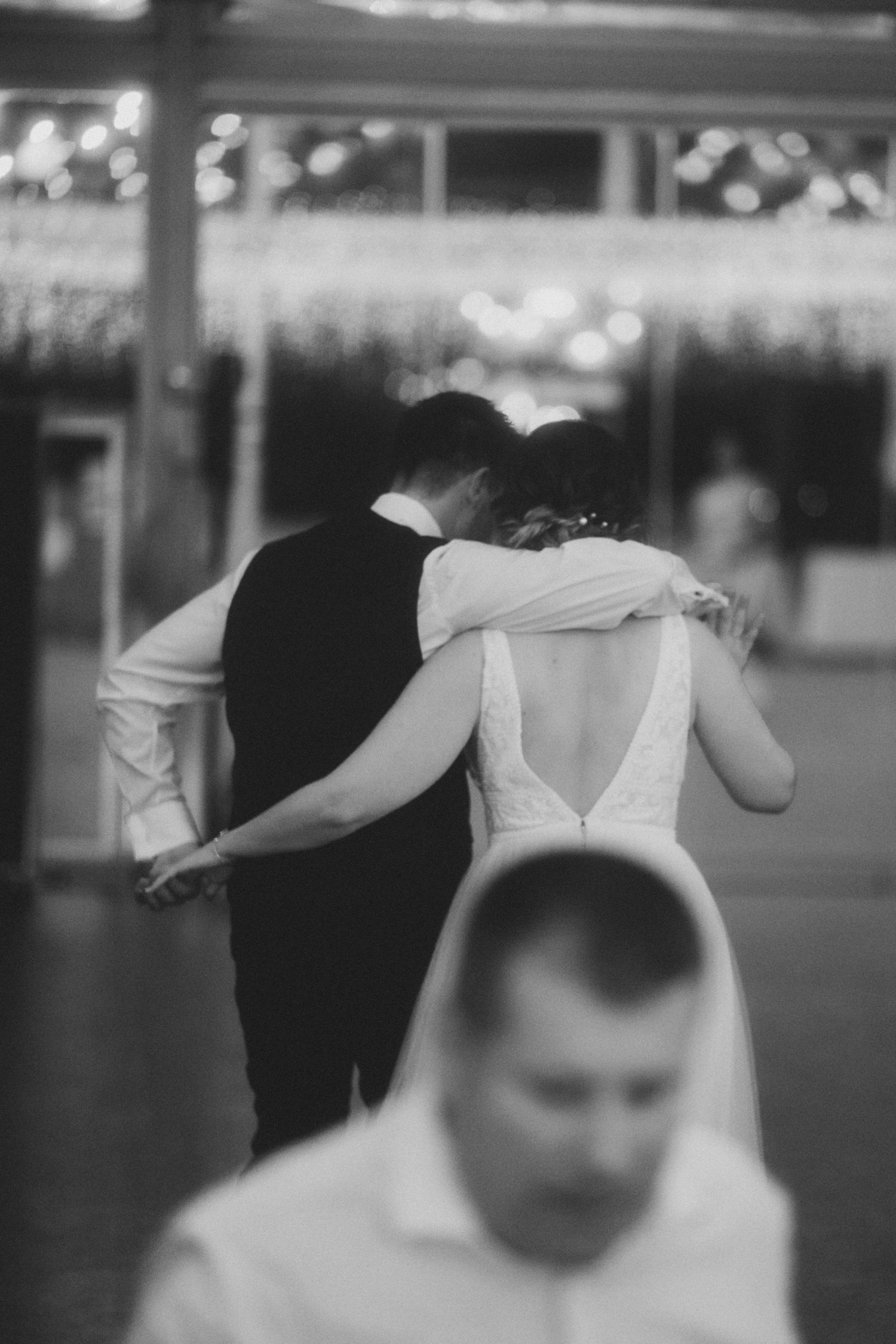 A black and white artistic wedding photo showing a couple in an intimate pose.
