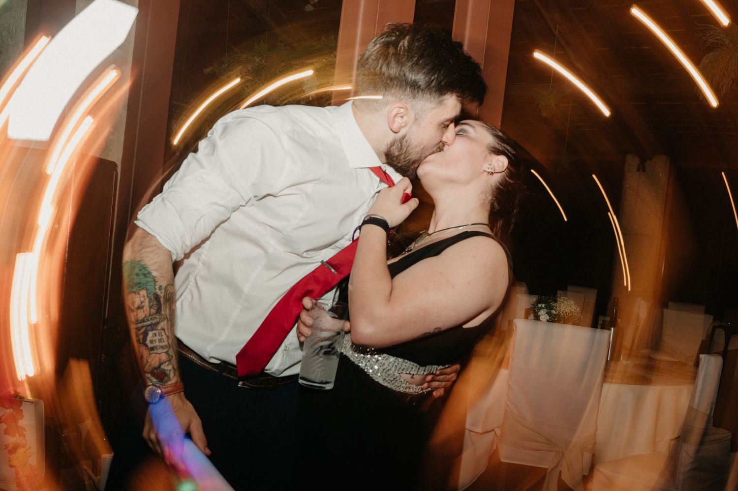 A couple shares a romantic dance moment at a wedding reception with warm lighting and motion blur.