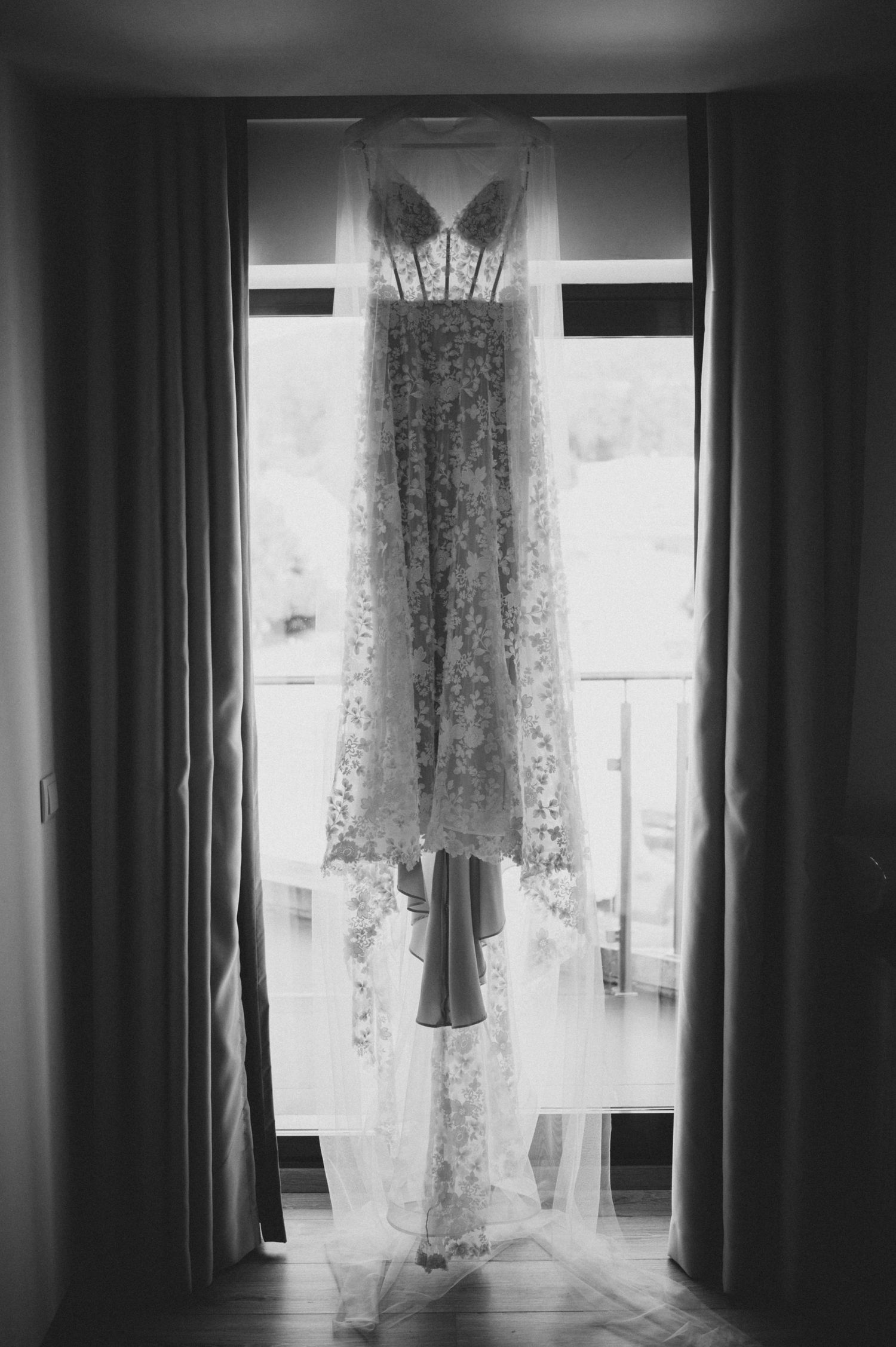 Black and white photograph of sunlight streaming through curtained windows in an empty room, creating dramatic shadows.