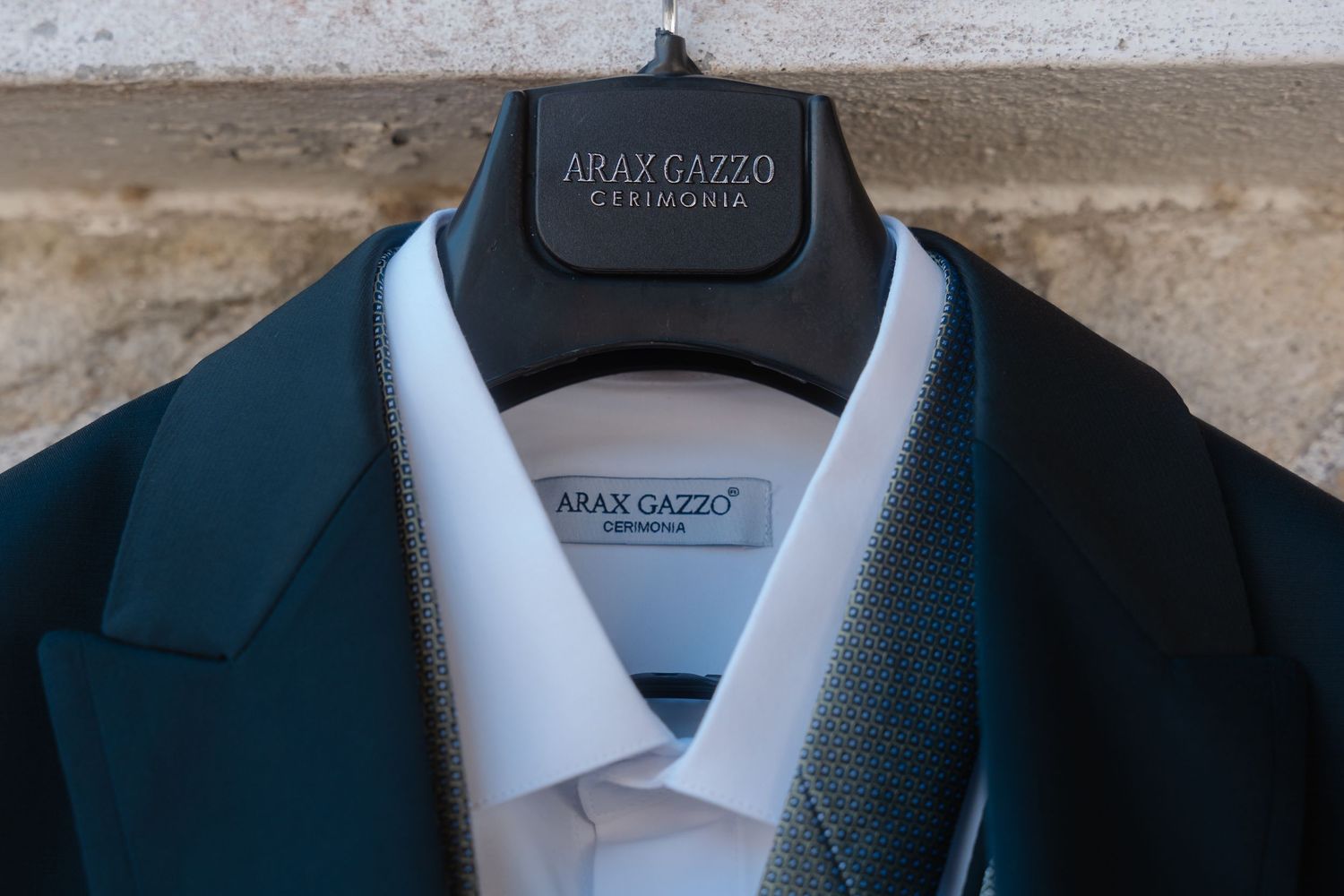 A series of black suit jackets and white dress shirts hanging on clothing racks in a retail store display.