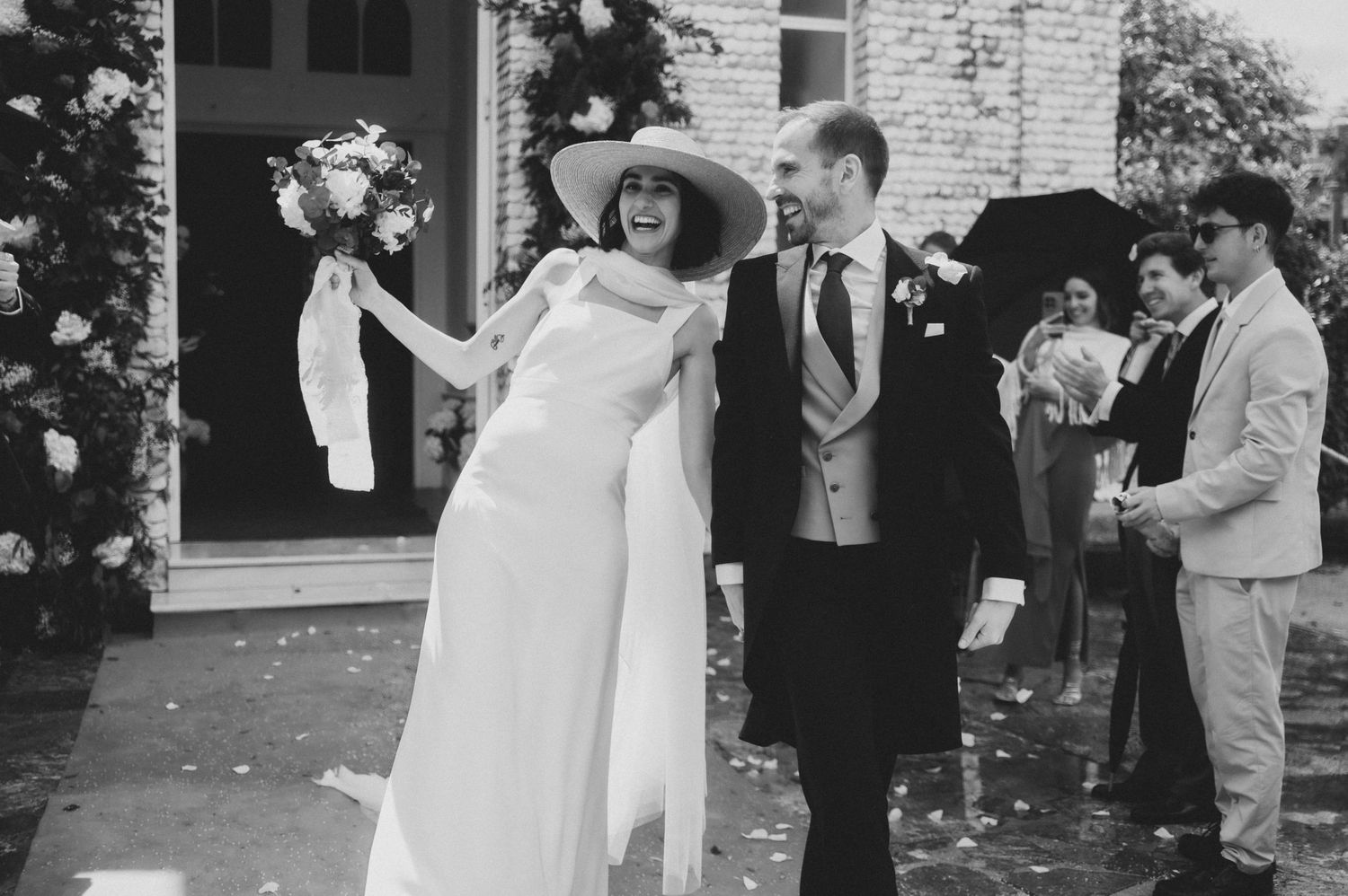 Wedding guests celebrating and throwing confetti during an outdoor ceremony.