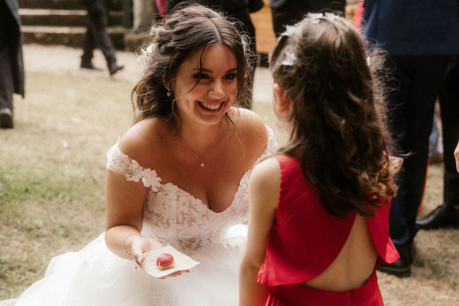 Wedding guests in red dresses gather around for celebratory moments at an outdoor reception.