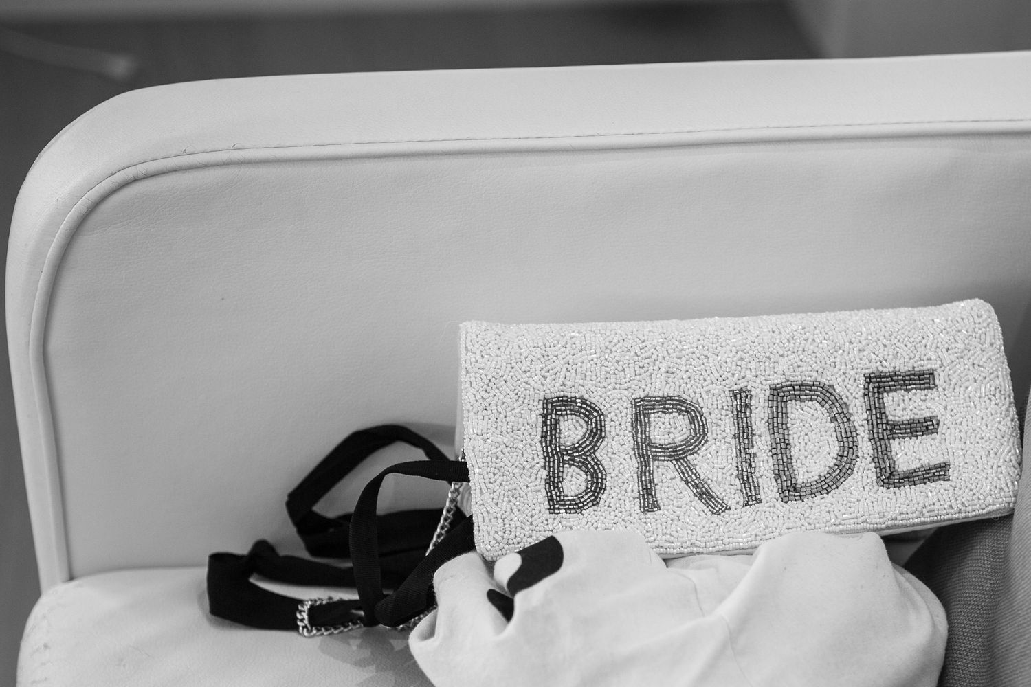 A black and white photo shows a 'BRIDE' sign mounted on a wall at a wedding venue.