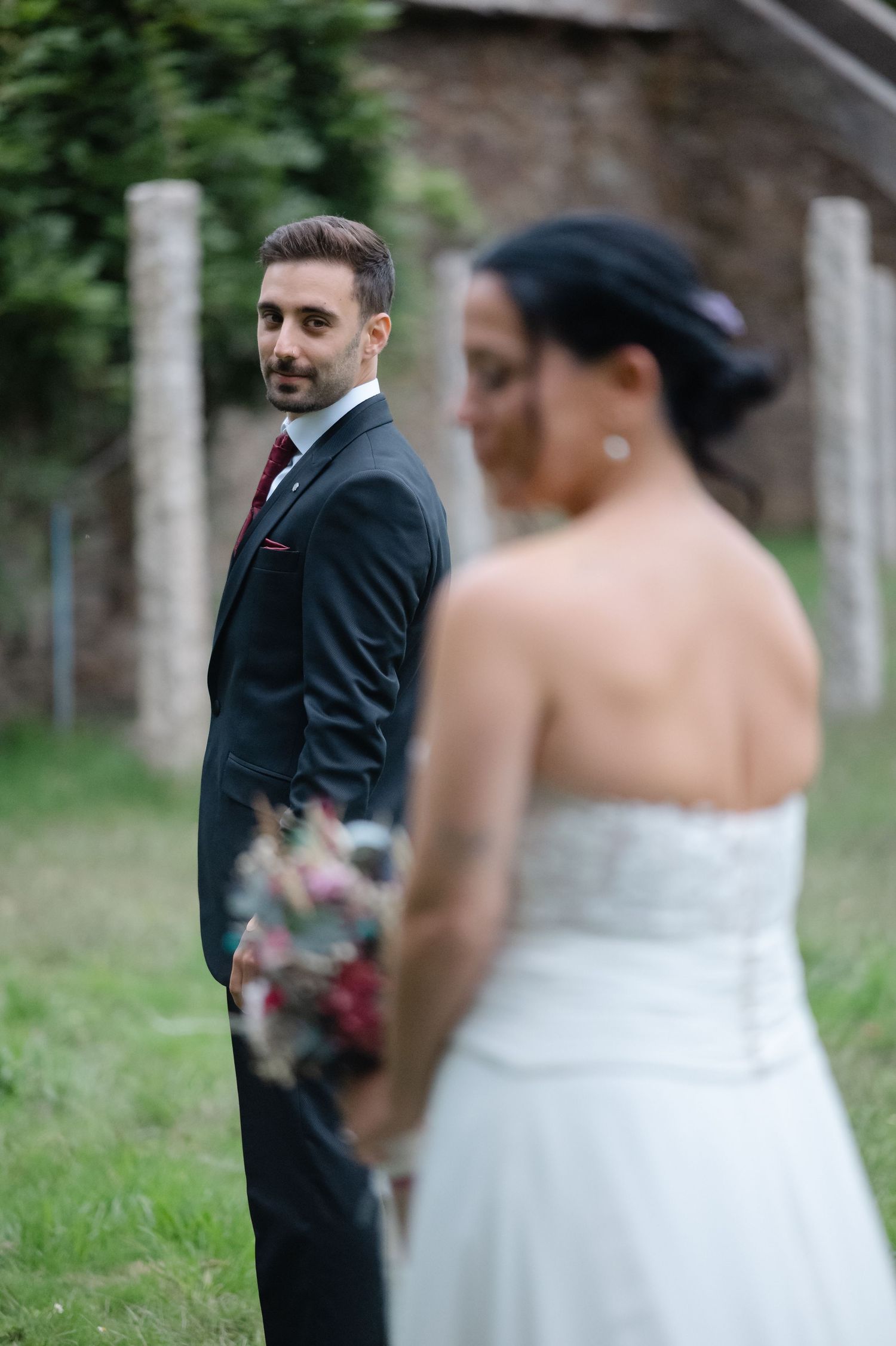 First look wedding moment captured as groom sees bride in white dress during outdoor garden ceremony.