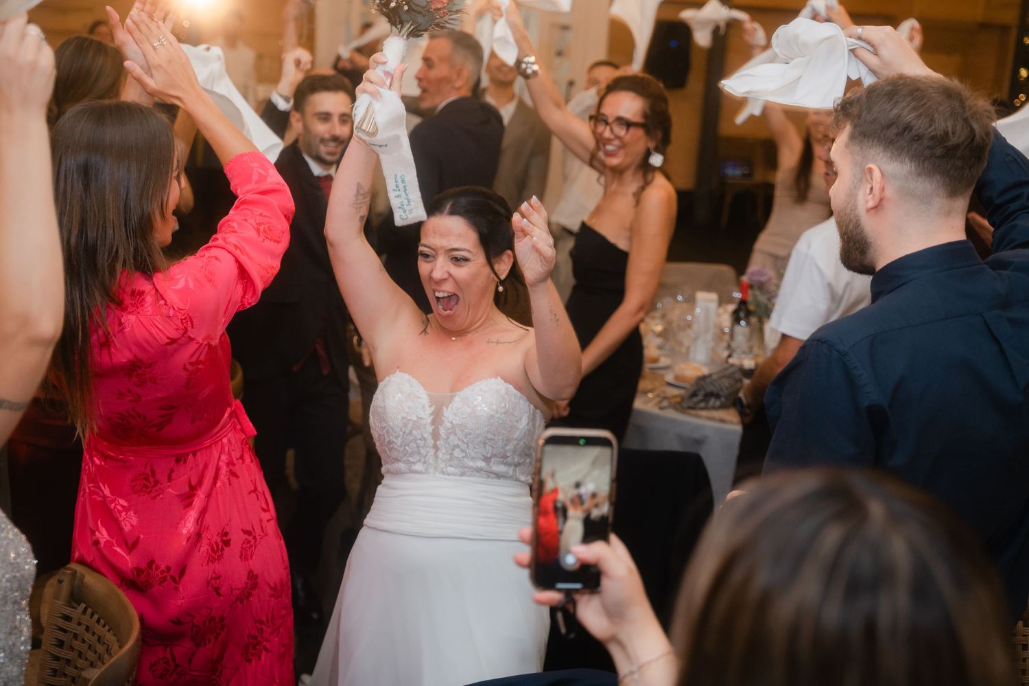 Wedding reception guests dancing and celebrating on a crowded dance floor with warm lighting.