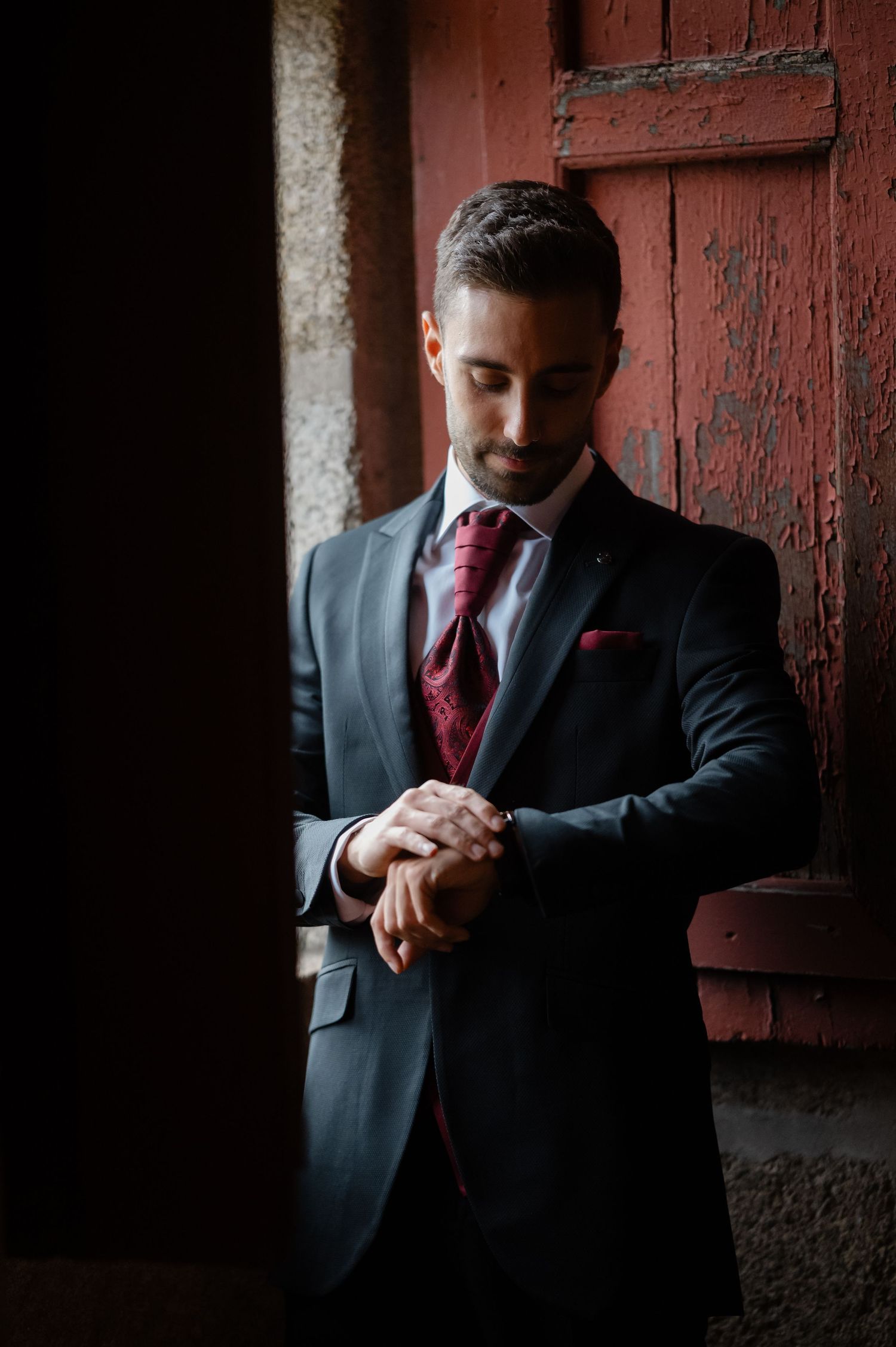 A series of dramatic photos showing a person in a dark suit and red tie checking their watch against a red brick wall.