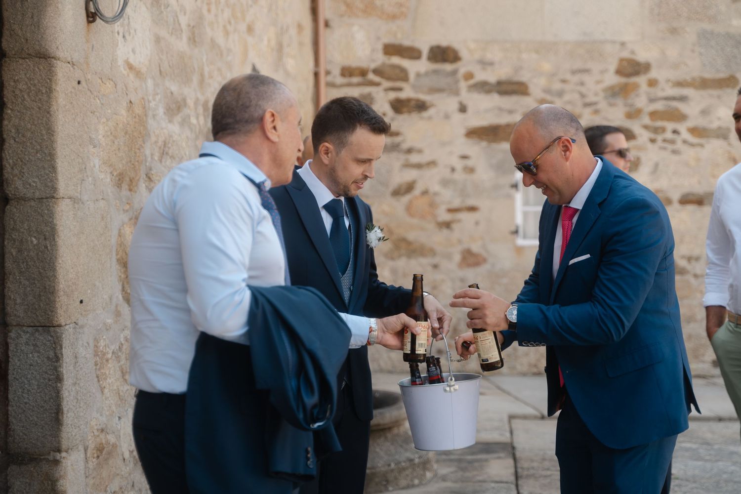 Two people in business attire engage in a close conversation against a stone wall background.