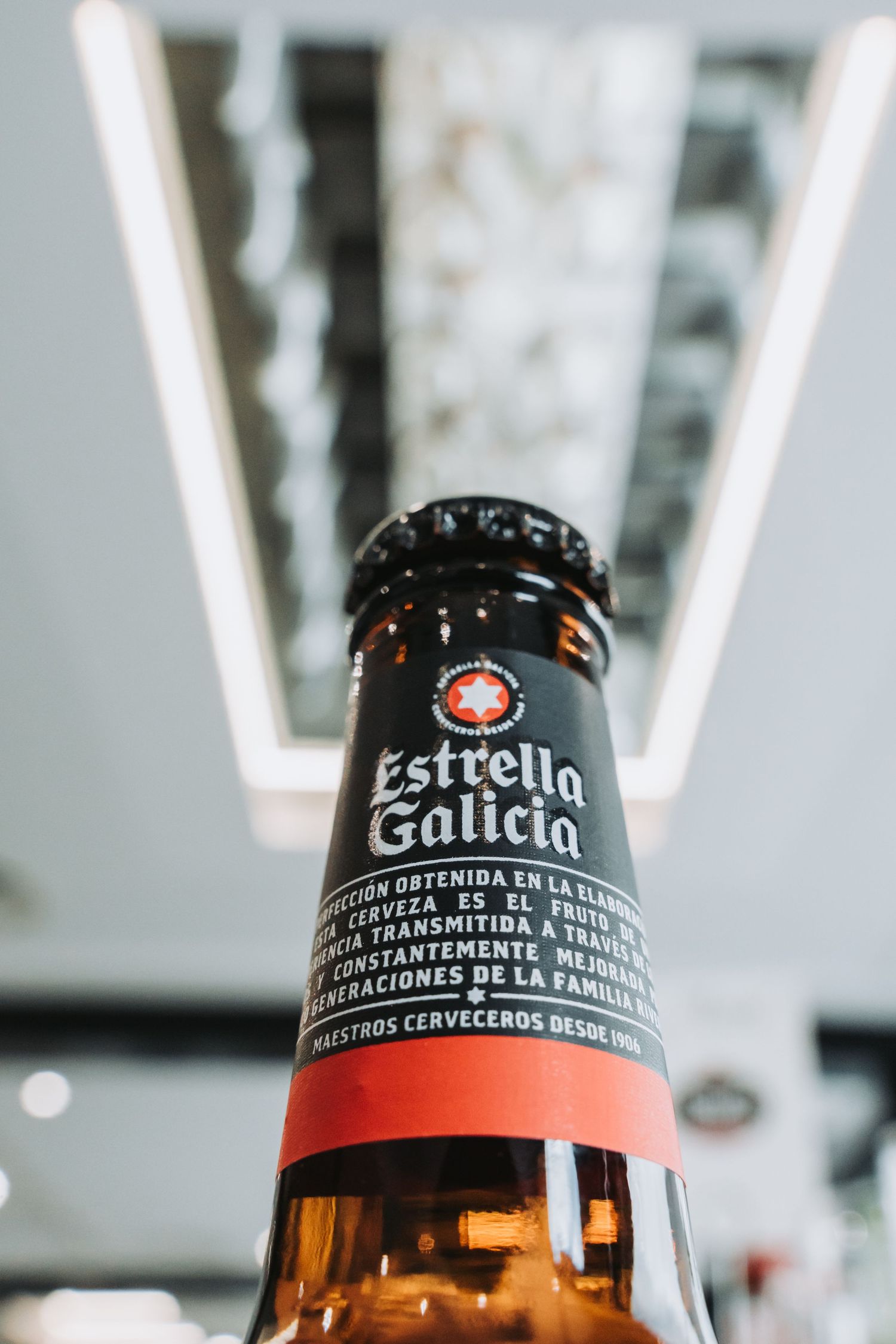 Close-up view of brown glass beer bottles with Estrella brand labels against a blurred white background.