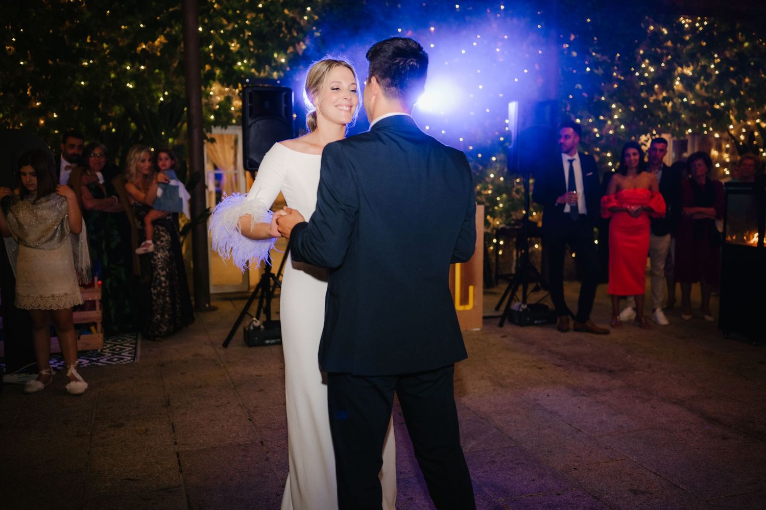 Couple sharing a romantic dance moment under twinkling lights at an evening wedding reception.