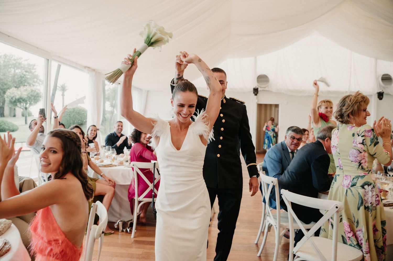 Wedding guests dance and celebrate on a light wooden dance floor during a reception.