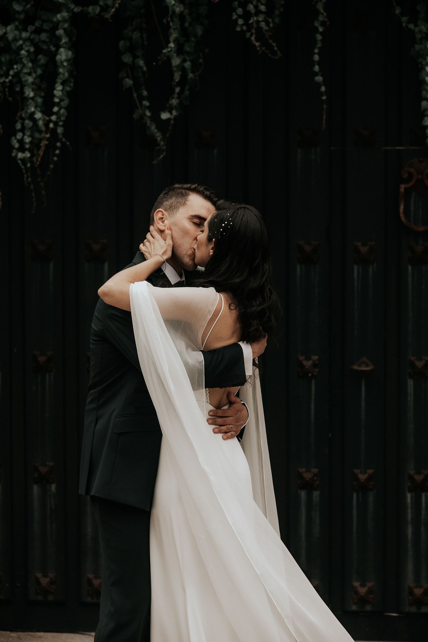 An intimate wedding embrace captured in a moody, dark setting with dramatic lighting.