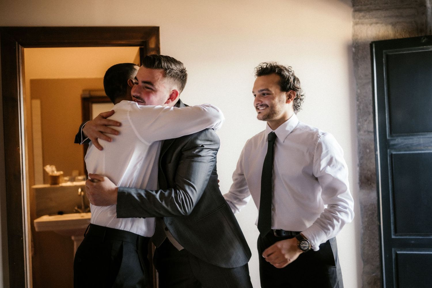 A sequence of black and white photographs showing people in formal attire embracing and greeting each other warmly.