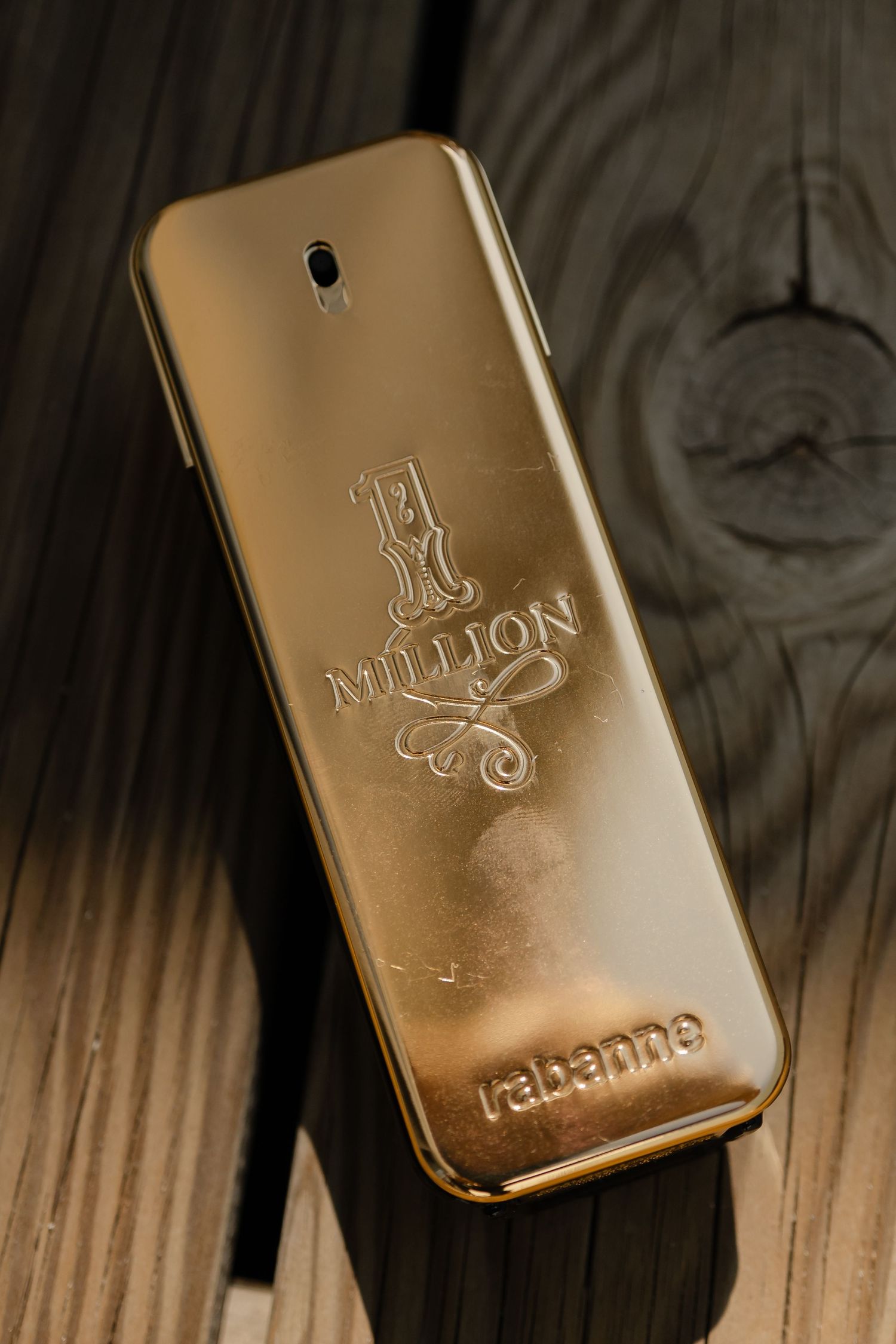Close-up view of gold-colored One Million Paco Rabanne perfume bottles on wooden surface showing luxury branding details.