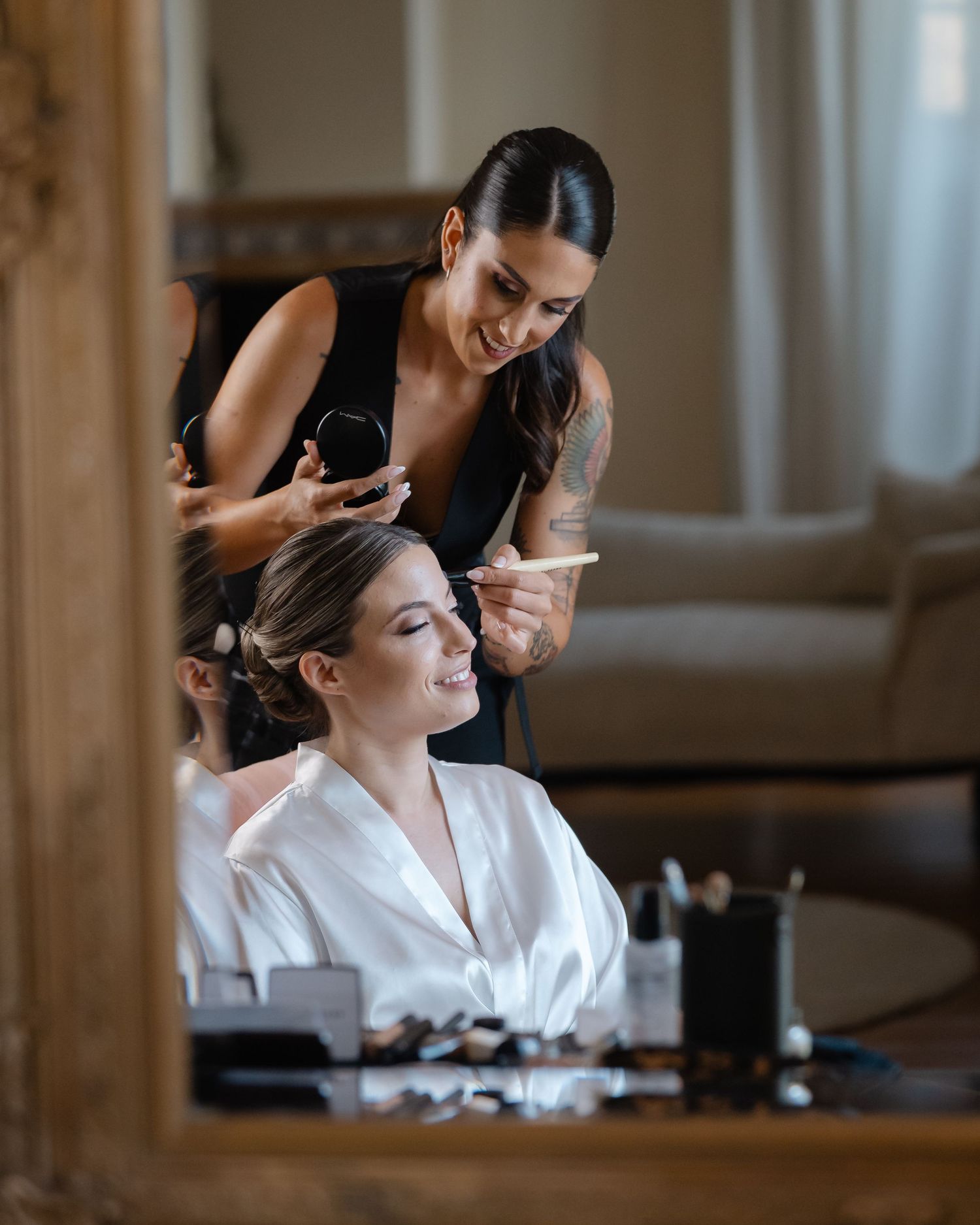 Makeup artist in black attire styling client's hair during wedding preparation.