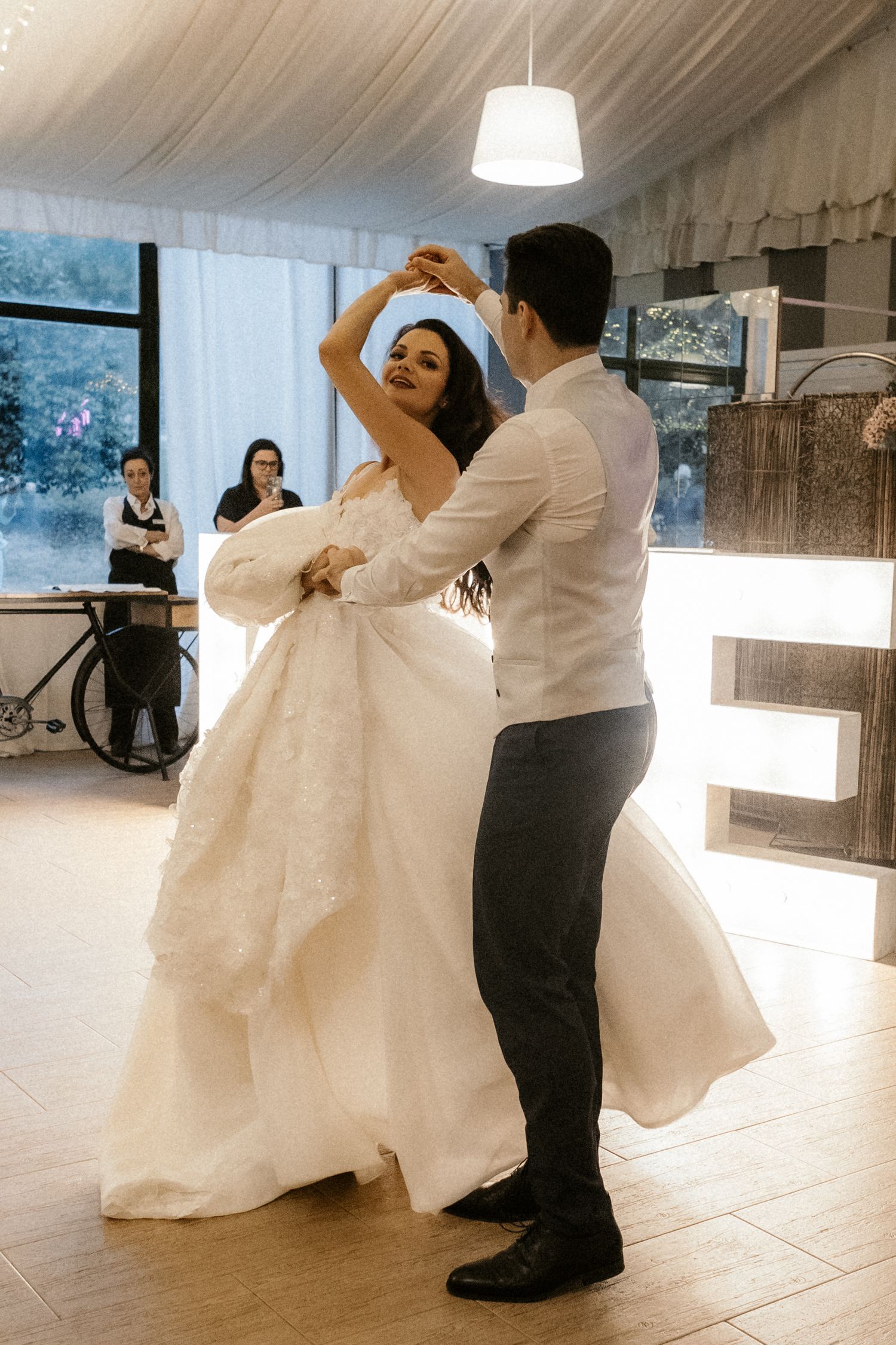Couples dancing together on a bright white dance floor during a wedding celebration.