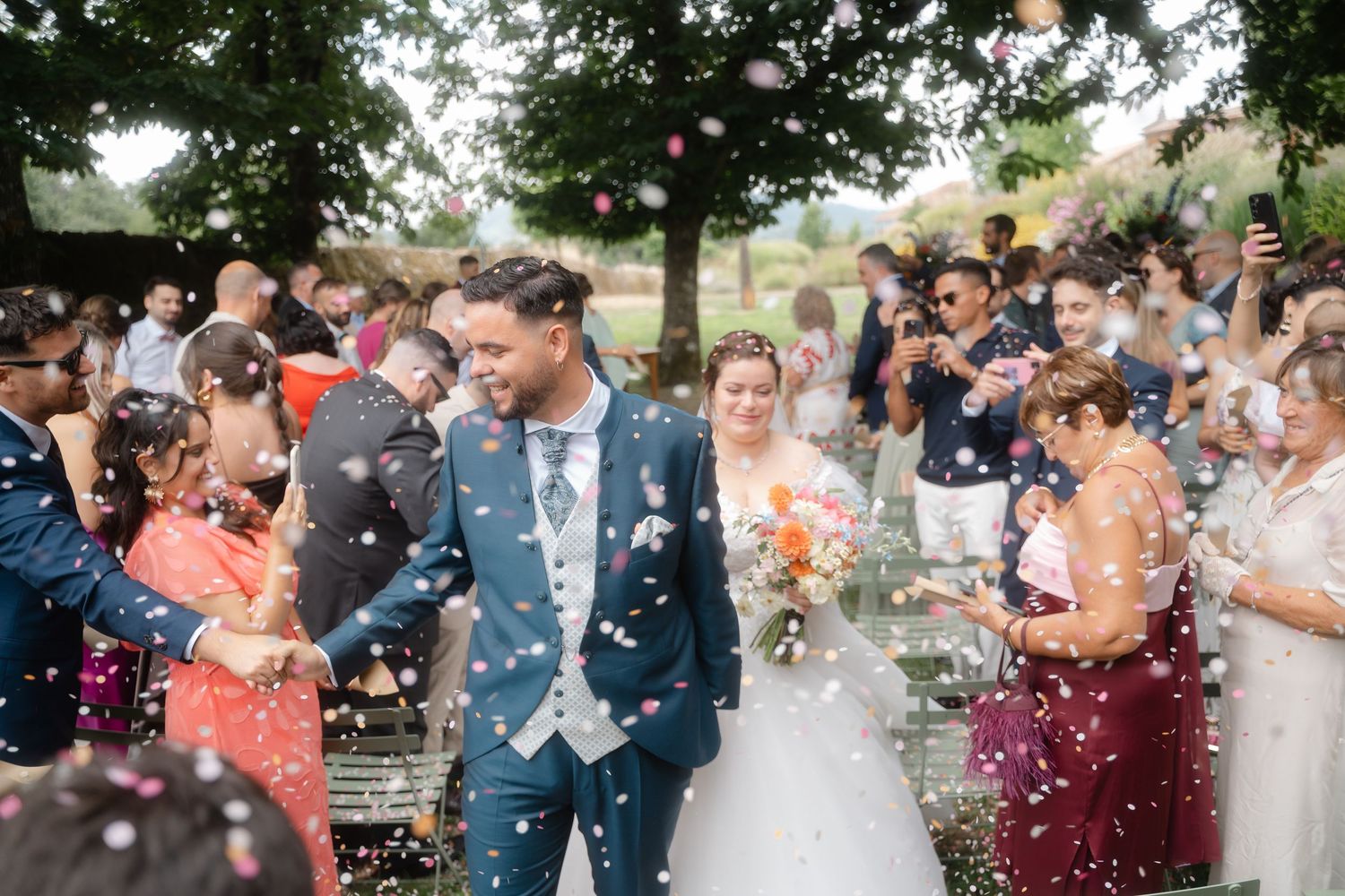 Wedding guests celebrate with confetti and bubbles during an outdoor ceremony celebration.