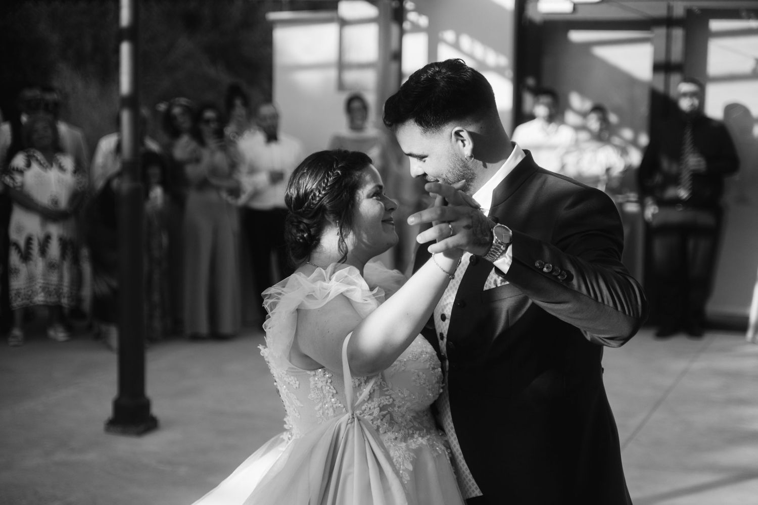 A couple shares their first dance at their wedding reception in a romantic black and white photograph.