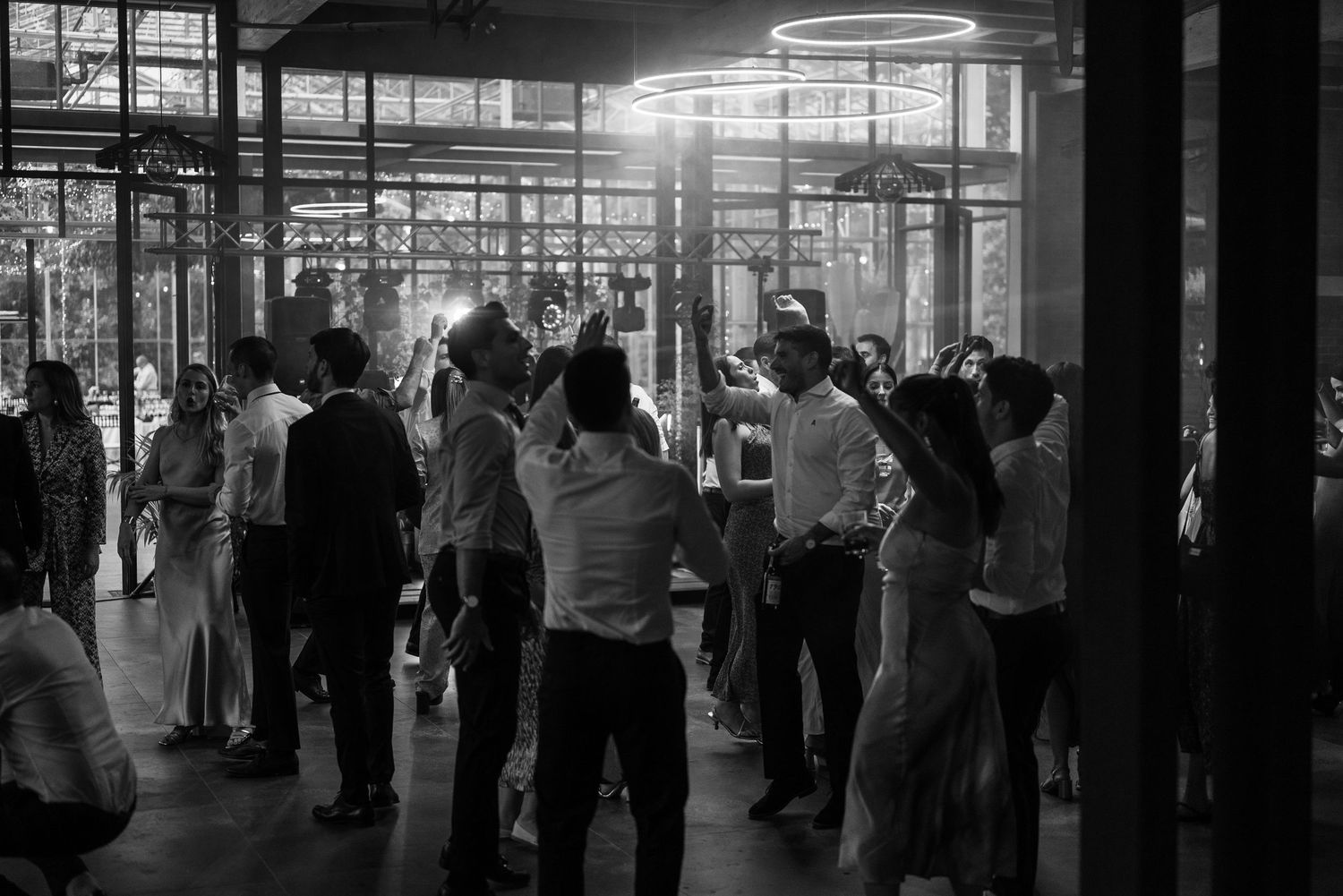 Silhouetted crowd gathers in large industrial space with bright natural light streaming through windows.
