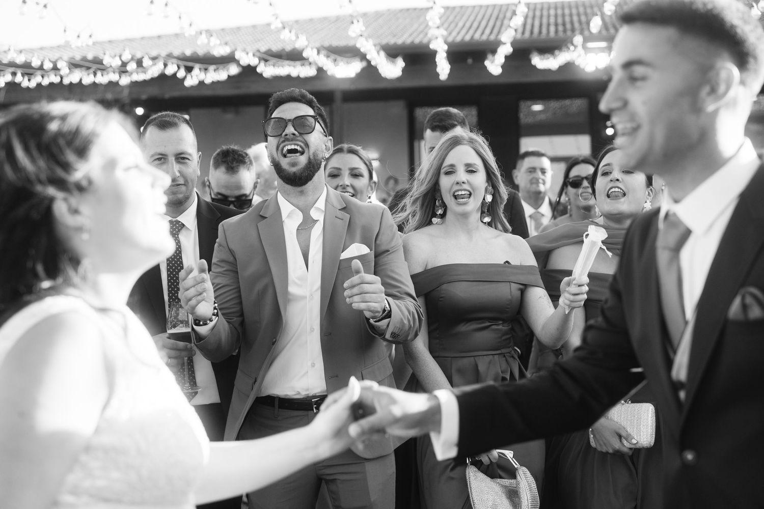 Wedding guests dancing and celebrating together at a lively reception in black and white.