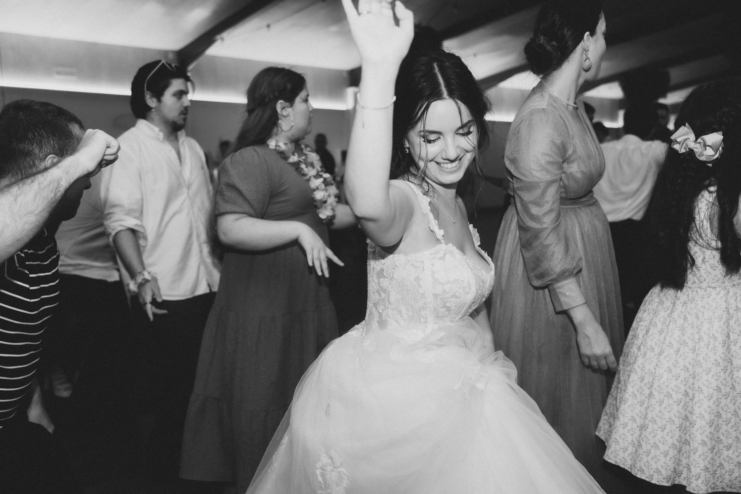 Wedding guests dancing and celebrating on a dance floor during a reception party.