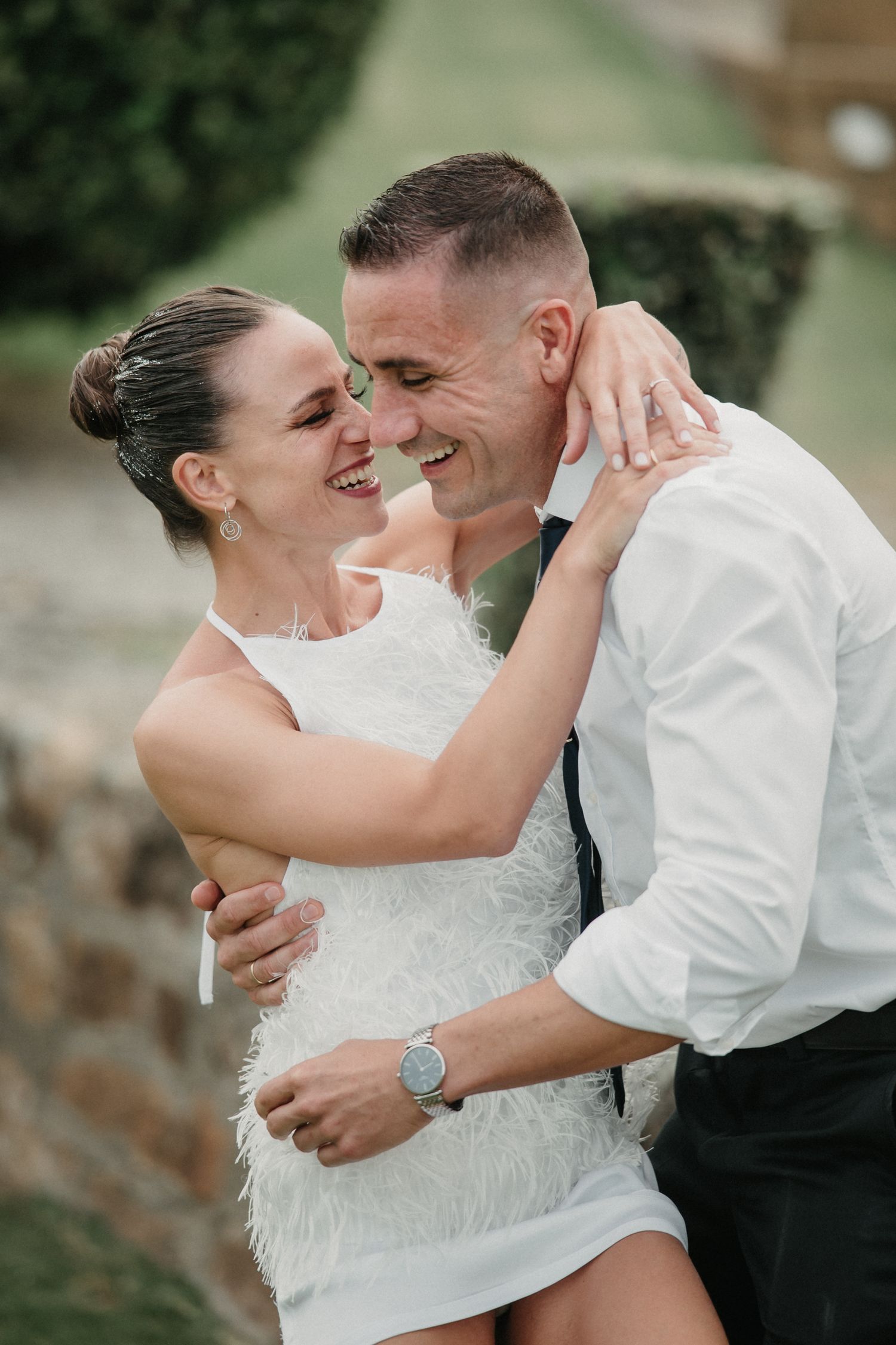 A couple in wedding attire share intimate embraces and joyful laughter during their outdoor photo session.