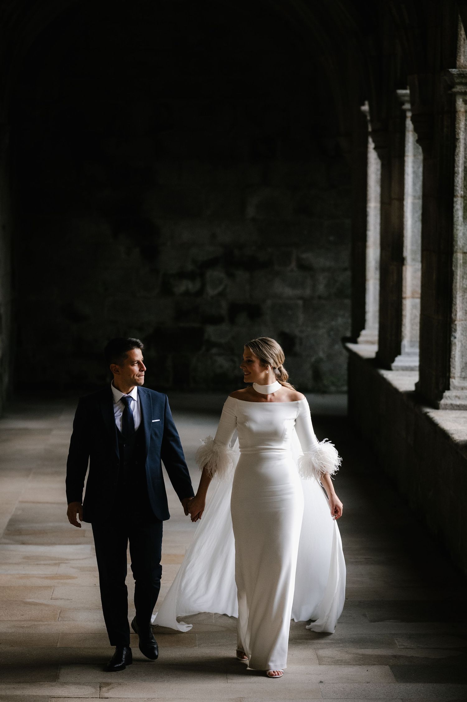 A series of dramatic black and white wedding photos showing a couple walking through a columned hallway.