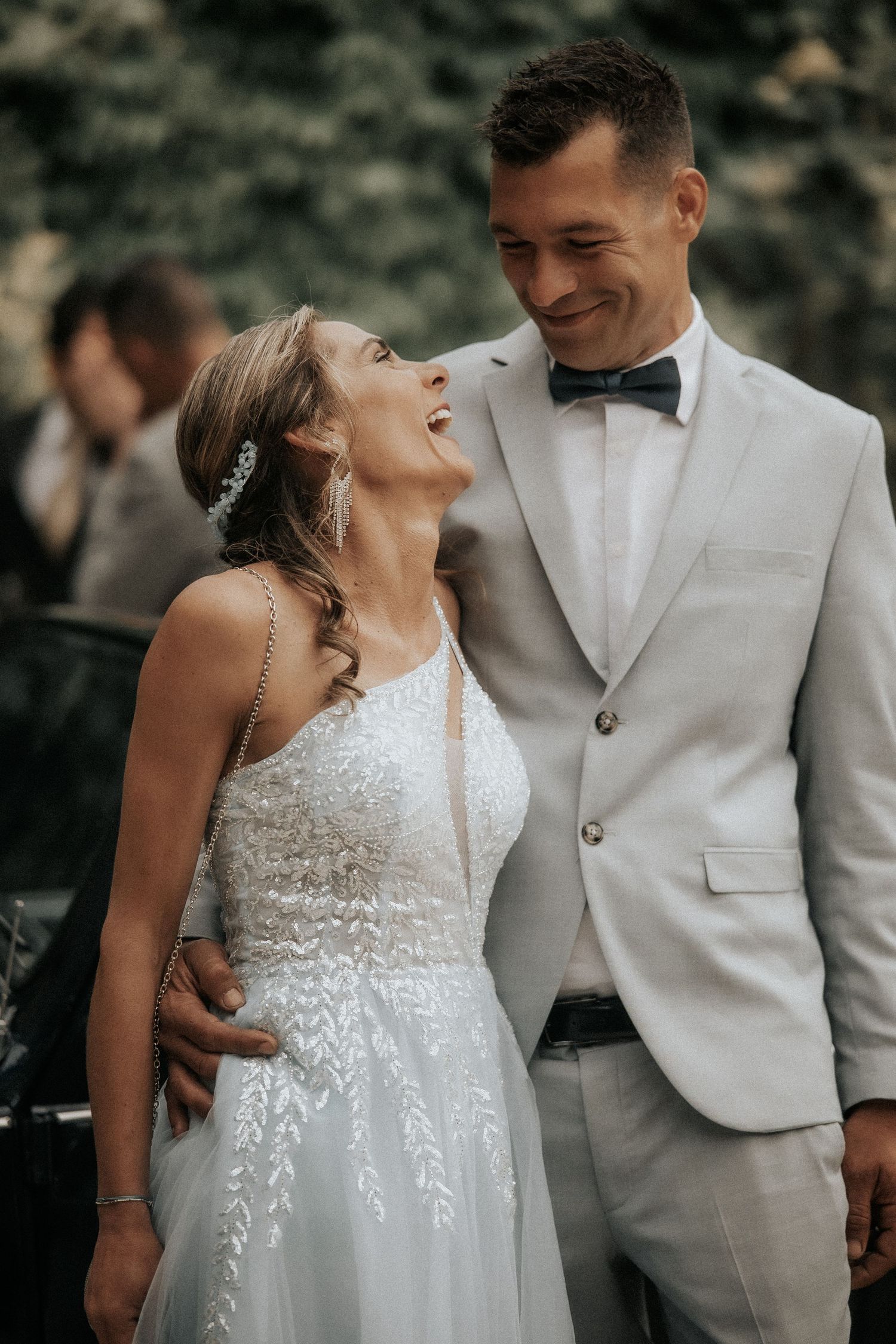 Couple in wedding attire sharing an intimate moment outdoors in natural lighting.