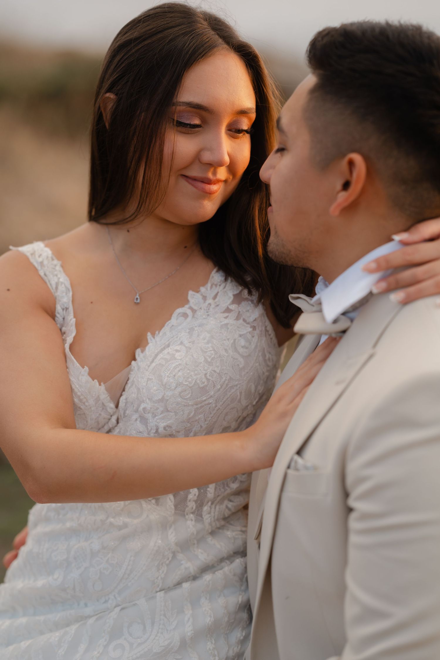Tender wedding couple moment captured in soft lighting with bride in lace dress.