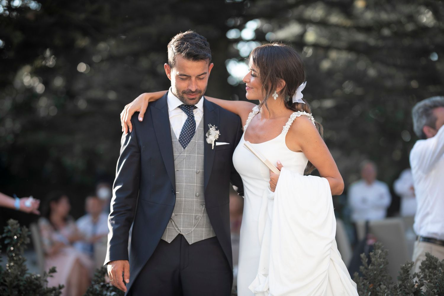 A couple shares a romantic dance moment at an outdoor wedding celebration as guests look on.